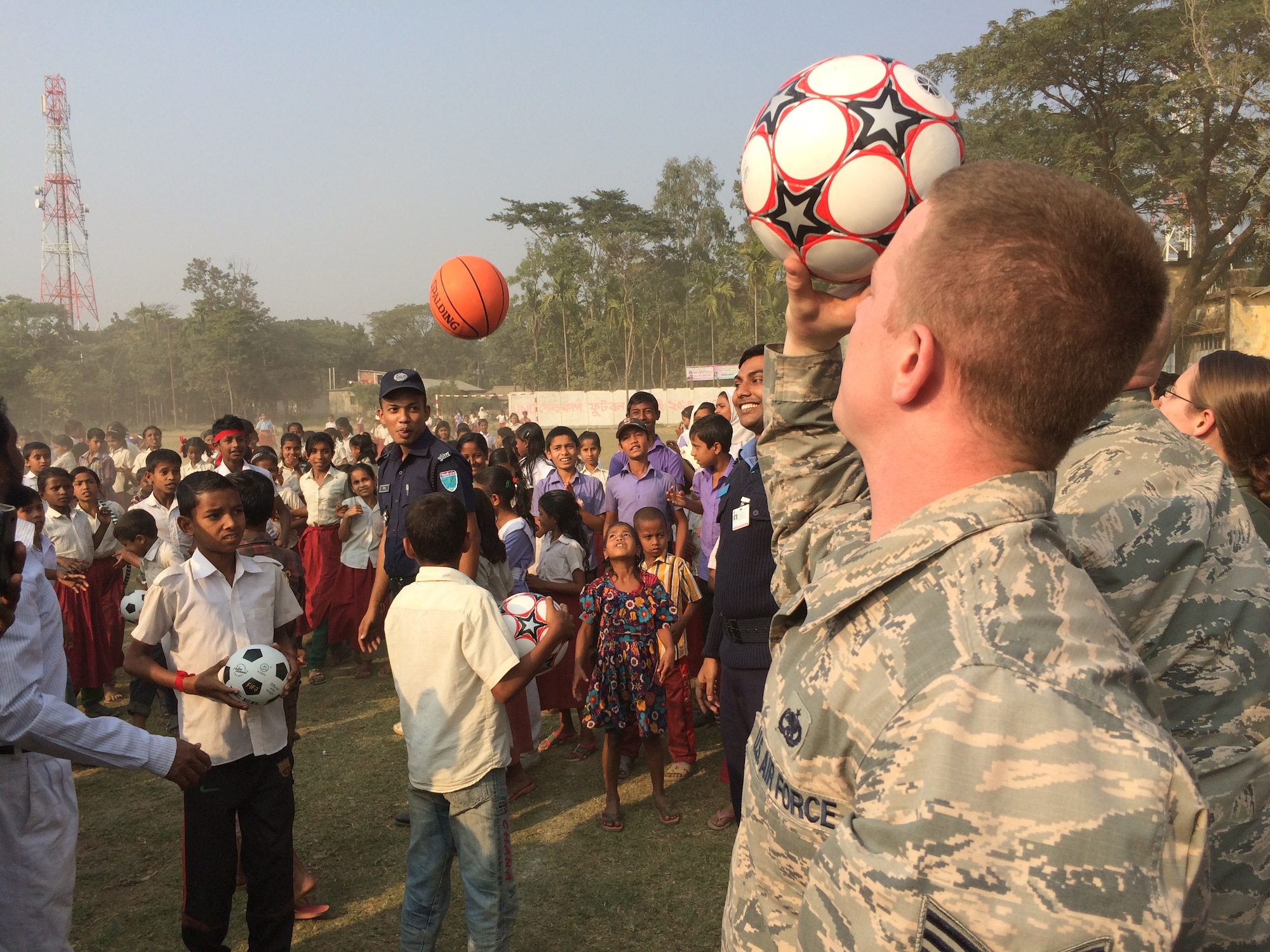 U.S. Air Force Staff Sgt. Tony Corman tosses a soccer ball to children at Goainghat Primary School in Sylhet, Bangladesh during Exercise COPE SOUTH, Jan. 28, 2015. Corman is assigned to the 374th Maintenance Squadron, Yokota Air Base, Japan. COPE SOUTH helps cultivate common bonds, foster goodwill, and improve readiness and compatibility between members of the Bangladesh and U.S. Air Forces. (U.S. Air Force photo by Senior Airman Ashley Powell/Released)
