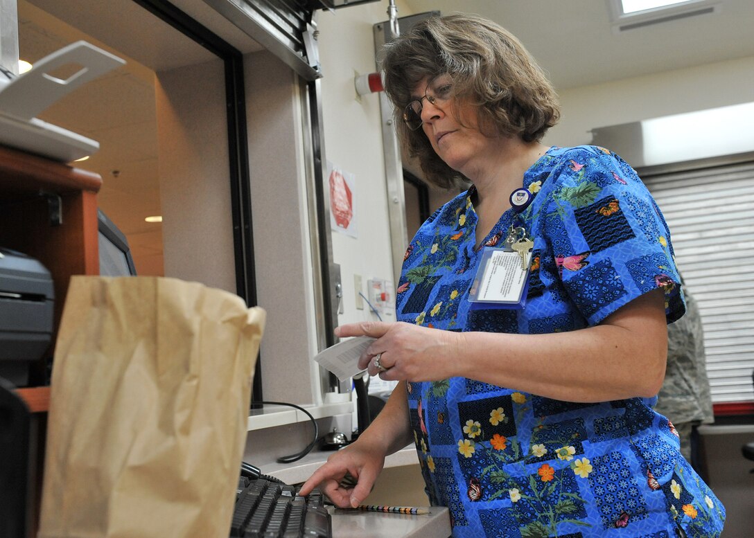 Sherry Morgan, 341st Medical Support Squadron pharmacy technician, dispenses a prescription to a patient Jan. 27 at the Malmstrom Air Force Base, Mont., pharmacy’s customer service window. Morgan also oversees the disposal of dangerous medications and substances. (U.S. Air Force photo/John Turner)