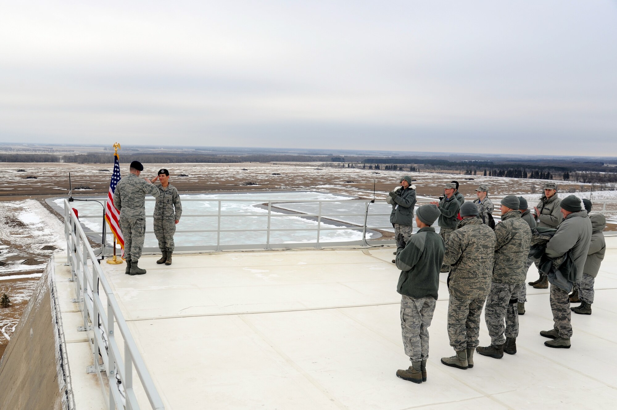 Airmen applaud Senior Airman Ninoska Williams-Sequiera, 319th Security Forces Squadron commander's support staff, following her reenlistment in the U.S. Air Force from atop the Precision Acquisition Radar building on Cavalier Air Force Station, N.D., January 30, 2014. Williams-Sequiera was administered the Oath of Enlistment by 319th SFS Commander Lt. Col. Jeffery Becker. (U.S. Air Force photo/Staff Sgt. David Dobrydney)