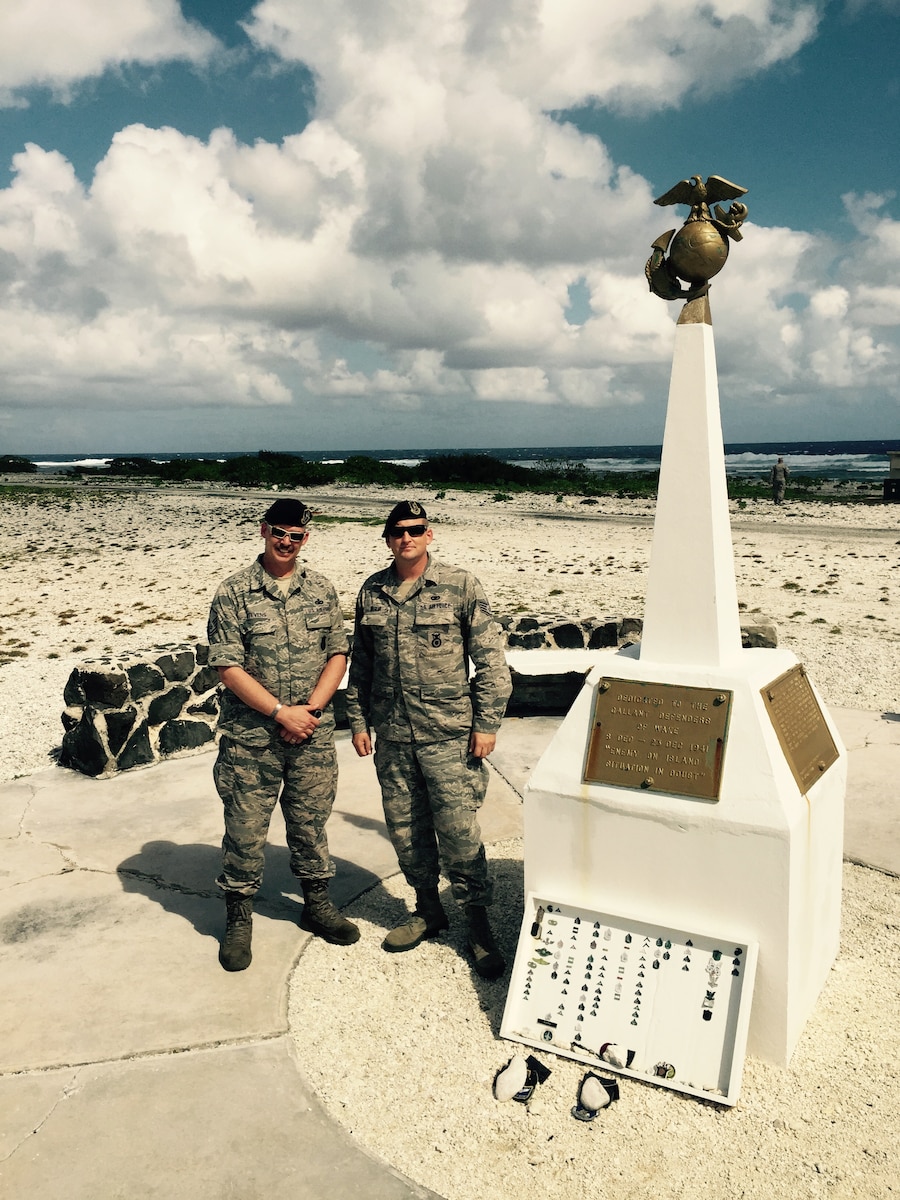 U.S. Air National Guard Master Sgt. Michael Stevens (left) and Staff Sgt. Sonny DaSilva with the 146th Airlift Wing Security Forces, stand next to a memorial on Wake Island enroute to Guam January 26, 2015. (U.S. Air National Guard photo by Airman 1st Class Madeleine Richards/Released)