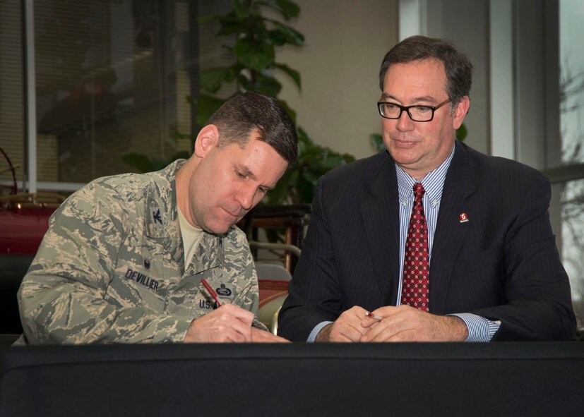 Col. John Devillier, Wright-Patterson Air Force Base commander, and Dr. Steven Johnson, Sinclair Community College president and CEO, sign a certificate of education exchange Jan. 22 at Sinclair. The certificate signifies the next step in a new partnership between the two organizations. The exchange is part of an Air Force community partnership program, P4, which allows installation agencies and community leaders to develop ways to share capabilities and resources. (Air Force photo by Michelle Gigante)
