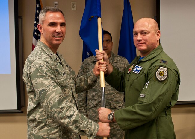 Brig. Gen. Stephen Whiting, U.S. Air Force Warfare Center vice commander, passes the Air Force Joint Test Program Office’s new guidon to Col. David Lünger, AFJO commander, after accepting the new colors during AFJO’s realignment ceremony at Nellis Air Force Base, Nev., Jan. 23, 2015. The acceptance of the colors by Whiting symbolizes the USAFWC’s acceptance of responsibility for AFJO. (U.S. Air Force photo by Staff Sgt. Siuta B. Ika)