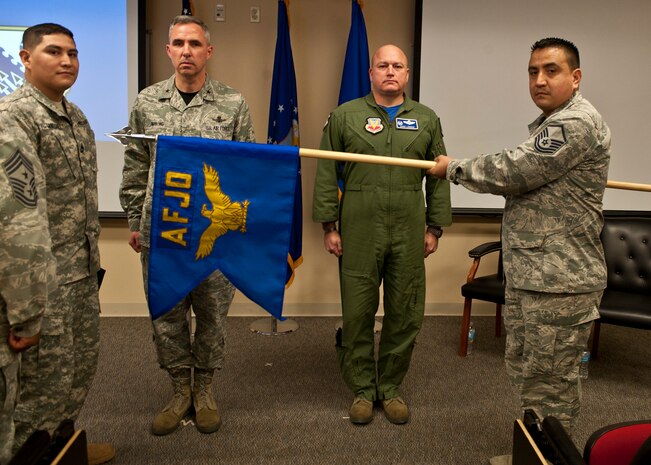 Members of the Air Force Joint Test Program Office pose for a photo with their new colors and Brig. Gen. Stephen Whiting (second from left), U.S. Air Force Warfare Center vice commander, after unfurling their new unit guidon during a realignment ceremony at Nellis Air Force Base, Nev., Jan. 23, 2015. AFJO’s realignment under the USAFWC ensures the unit will be able to continue its mission of generating, developing and supporting joint test activities that enhance Air Force capabilities and mission effectiveness in joint operations. (U.S. Air Force photo by Staff Sgt. Siuta B. Ika)