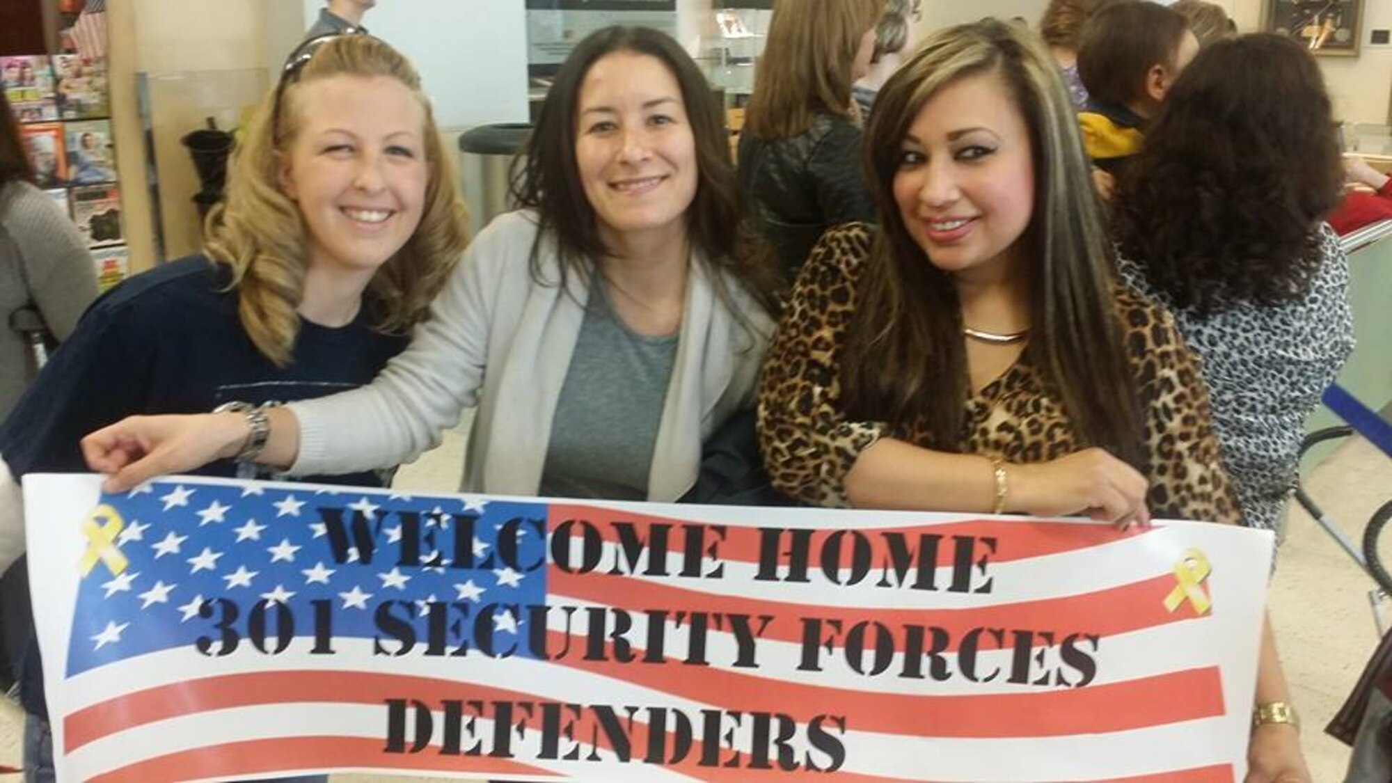 NAVAL AIR STATION FORT WORTH JOINT RESERVE BASE, Texas - Staff Sgt. Stephanie Abney, Tech. Sgt. Jennifer Martinez, and Staff Sgt. Veronica Fernandez, all 301st Security Forces Squadron members, display a welcome home banner after they arrived Jan. 24 at Dallas Fort Worth International Airport. Fourteen 301 SFS members returned home following a six-month deployment to Southwest Asia. (U.S. Air Force photo/Tech. Sgt. Martha Klemm)