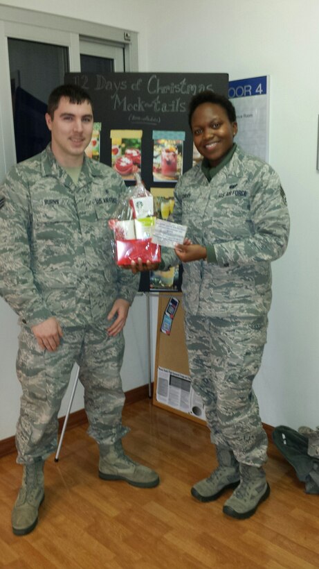Senior Airman Andrew Burns, mental health technician, 779 Medical Operations Squadron presents a holiday basket to the winner of  the Drunk and Drugged Driving Awareness pledge give-a-way contest, Senior Airman Nila Curry, 744th Communications Squadron.  An information table was set up at the Base Exchange on Dec. 16, 2014. Patrons were able to sign a pledge form, agreeing to practice safe precautions during the month of December. Alcohol and Drug Abuse Prevention Treatment Program (ADAPT) provides assessment, education and treatment for individuals involved with high-risk substance abuse or dependence. (AF Photo by Master Sergeant Kathleen Ivey)
