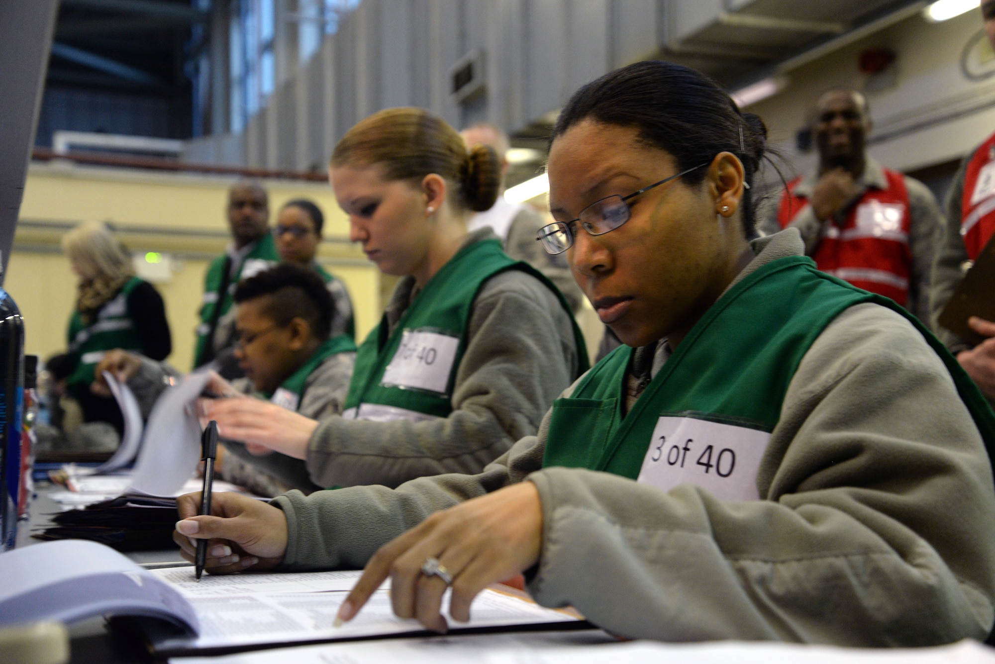 U.S. Air Force Staff Sgt. Kiana Williams, right, 100 Force Support Squadron NCO in charge of Force Management from Lompoc, Calif., reviews eligibility of tasked deployers in the personnel deployment function line during a base exercise Jan. 27, 2015 on RAF Mildenhall, England. The purpose of the PDF line is to test organizational and individual abilities to take care of personal issues prior to a deployment. (U.S. Air Force photo by Senior Airman Christine Griffiths/Released) 