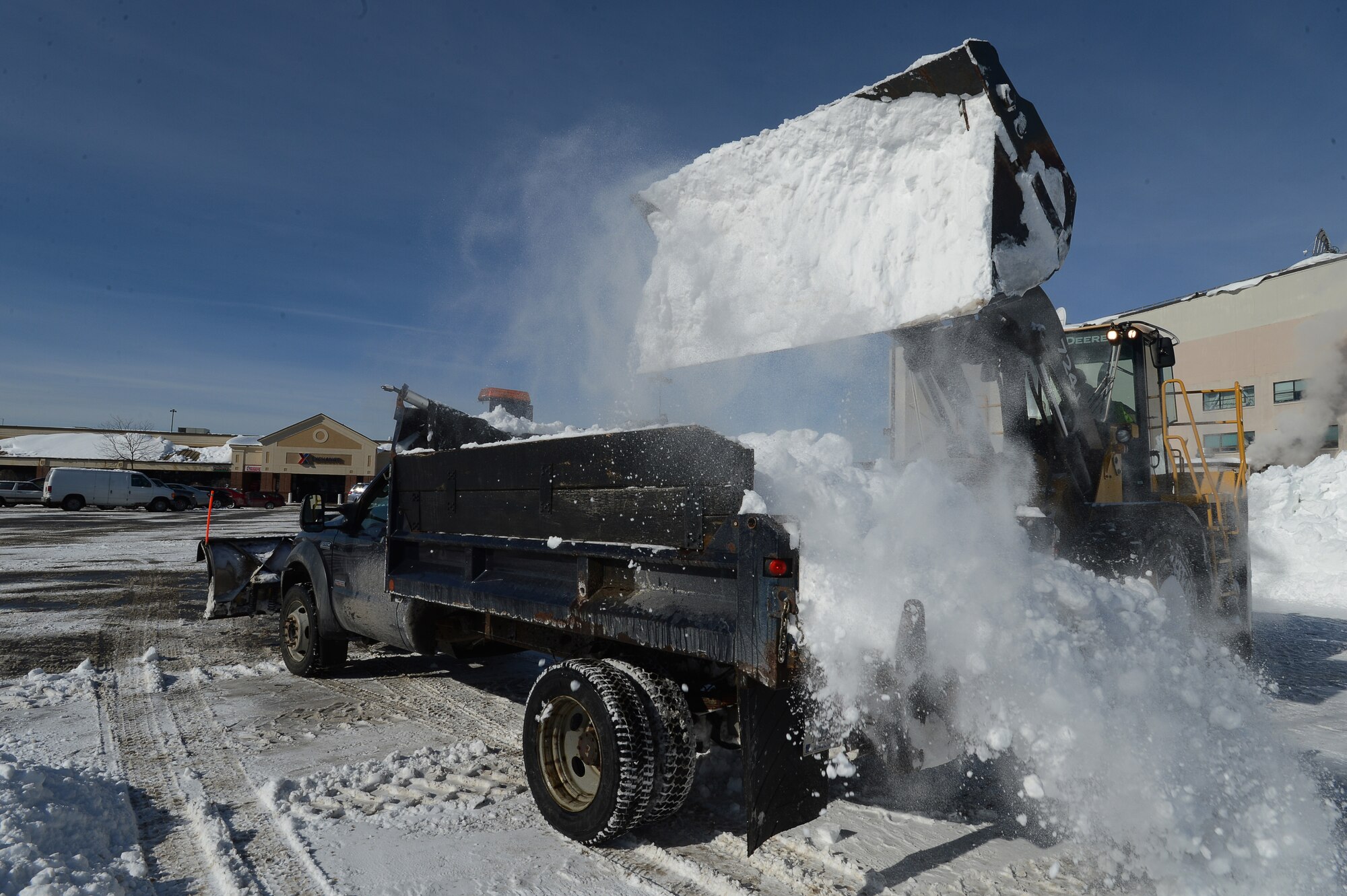 Mike Schubmehl, 66th Civil Engineering Division heavy equipment operator, dumps snow into the back of a pickup truck while cleaning up a parking lot on base after Winter Storm Juno, Jan. 29. The storm dropped several inches of snow on the region. (U.S. Air Force photo by Jerry Saslav)