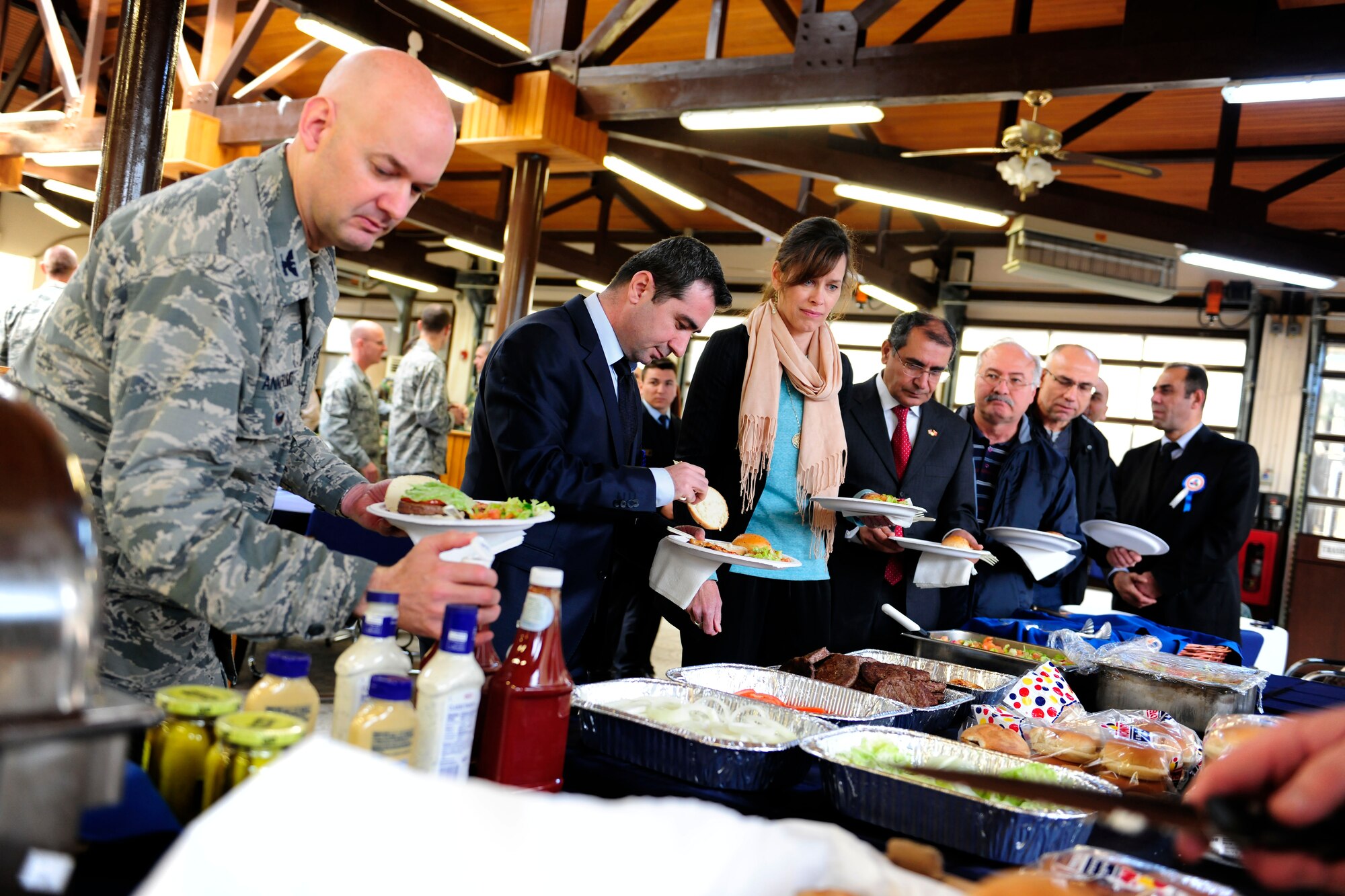 Members of the 39th Air Base Wing and Ministry of Customs and Trade customs agents serve themselves food during an International Customs Day luncheon Jan. 26, 2015, at Incirlik Air Base, Turkey. The luncheon featured a variety of American-style items such as barbeque. (U.S. Air Force photo by Senior Airman Krystal Ardrey/Released)