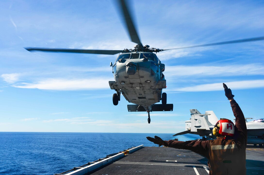 U.S. Navy Seaman Ryan Carpenter directs an MH-60S Seahawk from the Helicopter Sea Combat Squadron 8 during take off on the flight deck of the aircraft carrier USS John C. Stennis in the Pacific Ocean, Jan. 27, 2015. Carpenter is an airman.