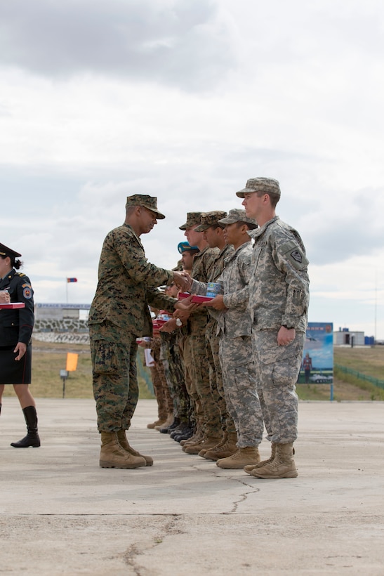 U.S. Marine Corps Col. Hector Velez, U.S. forces exercise director, presents a gift to Capt. Pancho Gonzales, U.S. Army Alaska’s 3rd Battalion, 21st Infantry Regiment, exercise platoon leader, during the Khaan Quest 2015 closing ceremony held in Tavantolgoi, Mongolia, July 1, 2015. Khaan Quest is a regularly scheduled, multinational exercise hosted annually by Mongolian Armed Forces and co-sponsored by U.S. Army Pacific, and U.S. Marine Corps Forces, Pacific. This year marks the 13th iteration of Khaan Quest.