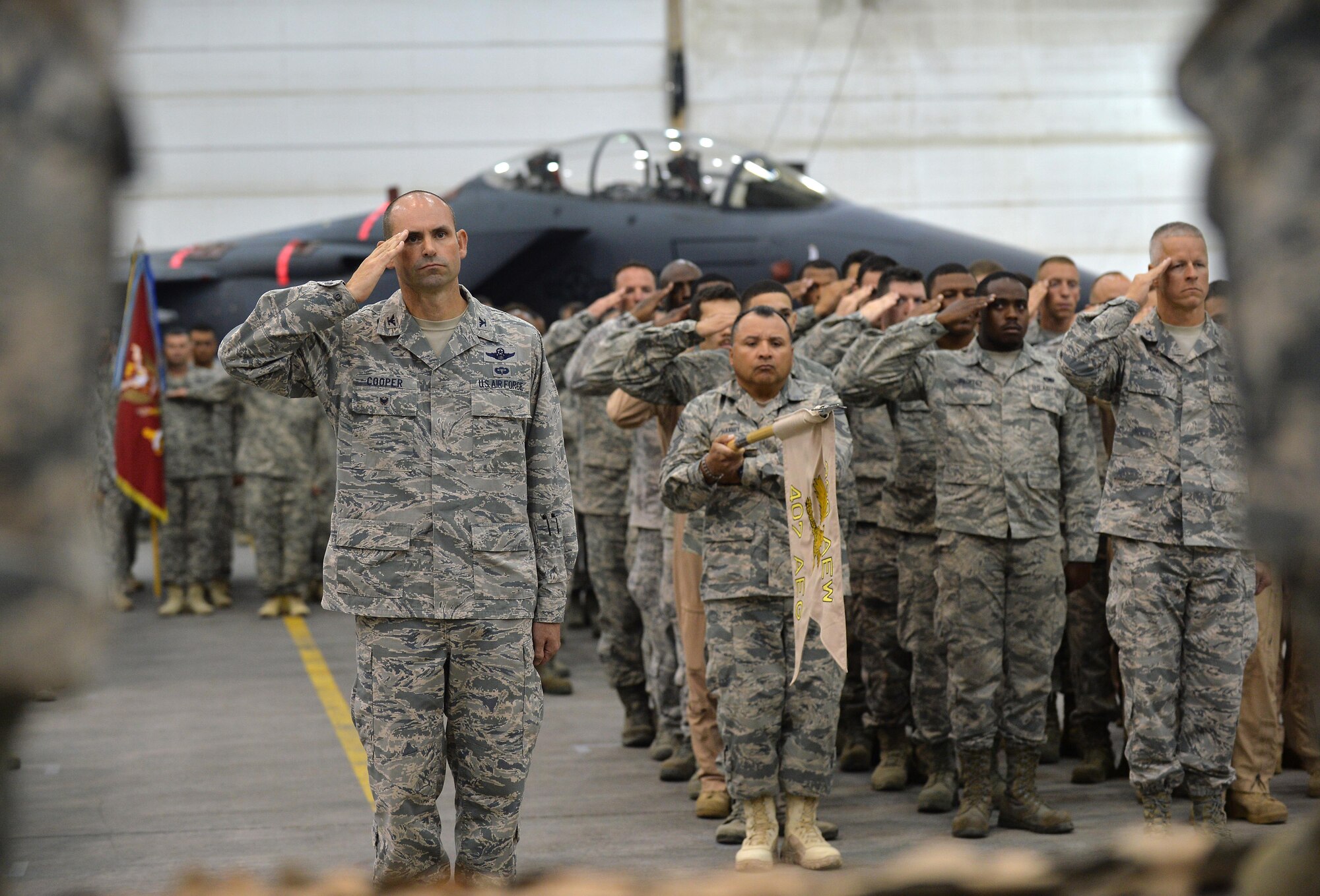 Airmen and Soldiers from the 380th Air Expeditionary Wing salute during the National Anthem at an undisclosed location in Southwest Asia June 30, 2015. The formations were part of the 380th AEW Change of Command ceremony, which saw Brig. Gen. John Quintas relinquish command to Brig. Gen. Daniel Orcutt. (U.S. Air Force photo/Tech. Sgt. Jeff Andrejcik)