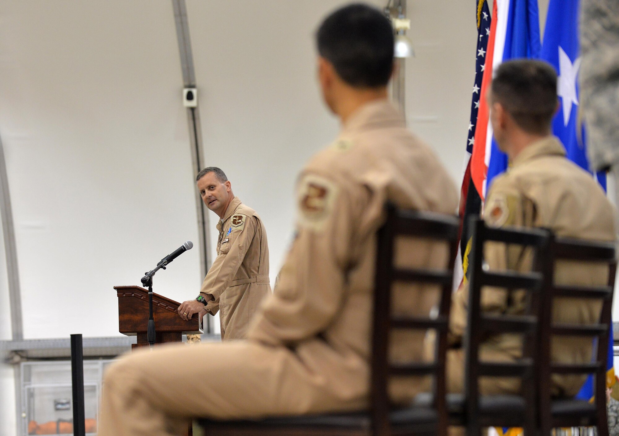 Brig. Gen. Daniel Orcutt looks back to thank Brig. Gen. John Quintas, seated left, during the 380th Air Expeditionary Wing change of command at an undisclosed location in Southwest Asia June 30, 2015. Orcutt, who comes from Hurlburt Field, assumed command of the 380th AEW from Quintas. (U.S. Air Force photo/Tech. Sgt. Jeff Andrejcik)