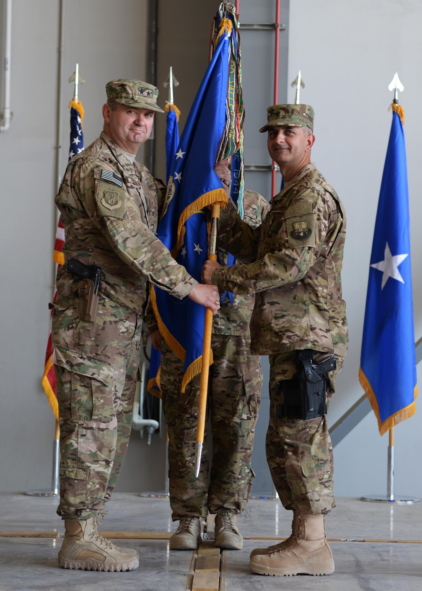 U.S. Air Force Maj. Gen. Scott West, 9th Air and Space Expeditionary Task Force-Afghanistan commander, hands the guidon to the new commander of the 455th Air Expeditionary Wing, Brig. Gen. Dave Julazadeh July 1, 2015, at Bagram Airfield, Afghanistan. (U.S. Air Force photo by Senior Airman Cierra Presentado/Released)  