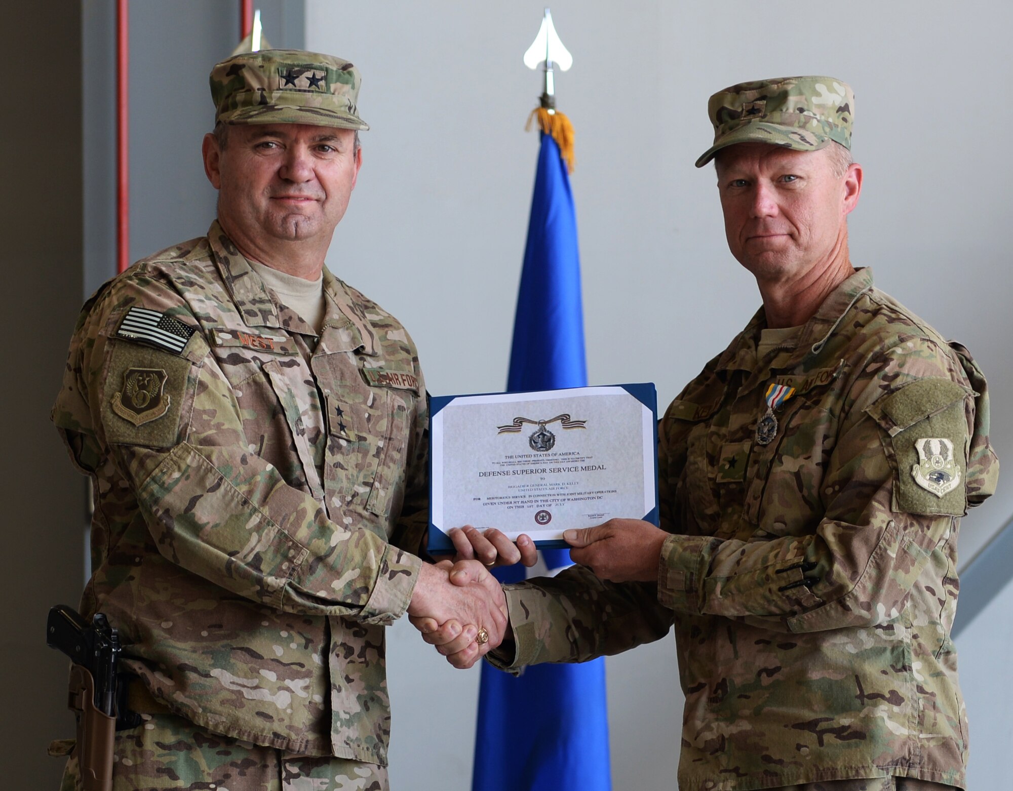U.S. Air Force Maj. Gen. Scott West, 9th Air and Space Expeditionary Task Force-Afghanistan commander, poses for a photo with Brig. Gen. Mark Kelly, 455th Air Expeditionary Wing commander, after receiving an end of tour decoration July 1, 2015, at Bagram Airfield, Afghanistan. Kelly relinquished command to Brig. Gen. Dave Julazadeh. (U.S. Air Force photo by Senior Airman Cierra Presentado/Released)