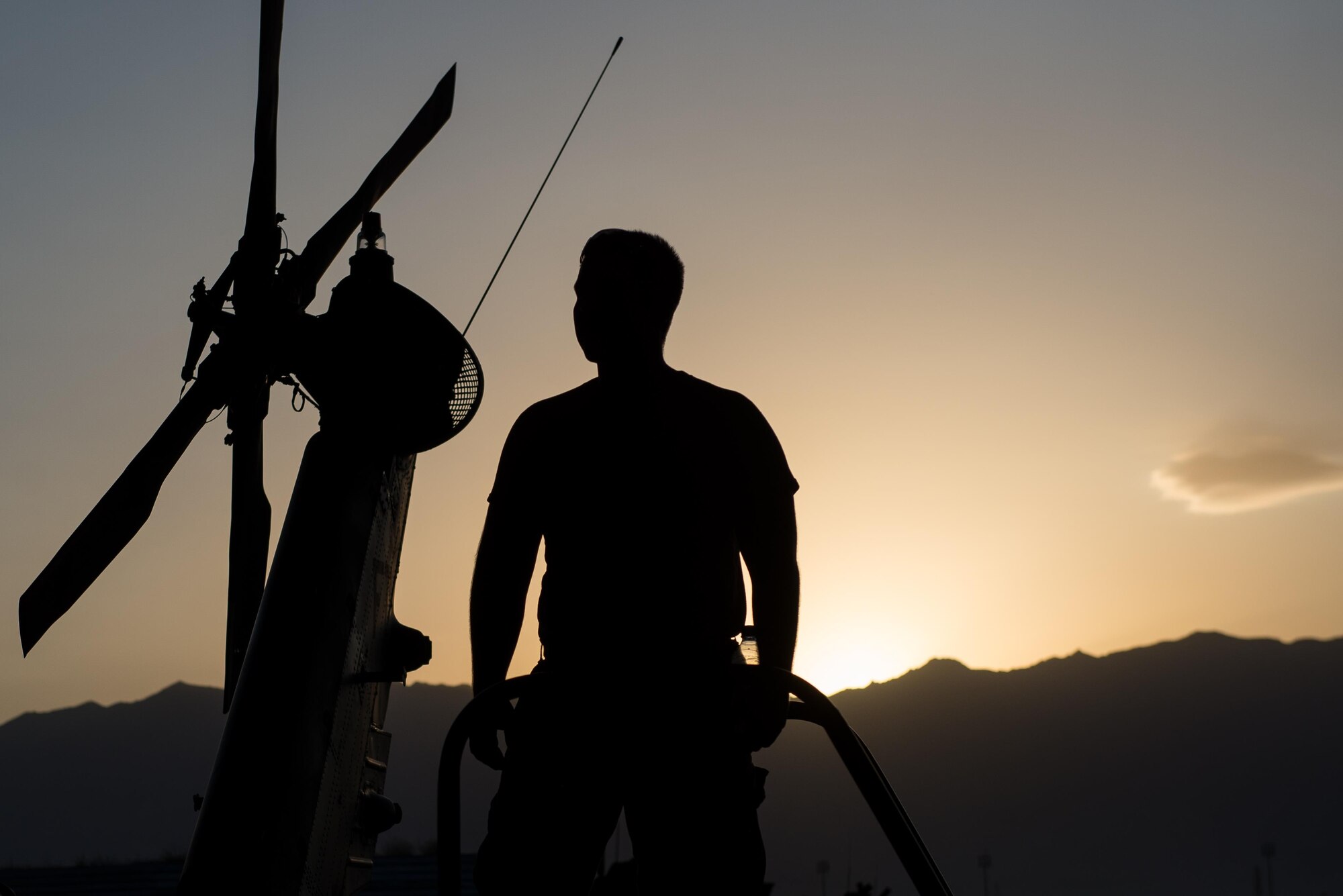 U.S. Air Force Senior Airman Joseph Roberts, 41st Expeditionary Helicopter Maintenance Unit crew chief, looks on as other Airmen complete a 50 hour inspection on a HH-60 Pave Hawk helicopter at Bagram Airfield, Afghanistan, June 28, 2015. The 41st EHMU ensure Pave Hawks on Bagram are prepared for flight and return them to a mission-ready state once they land.  (U.S. Air Force photo by Tech. Sgt. Joseph Swafford/Released)