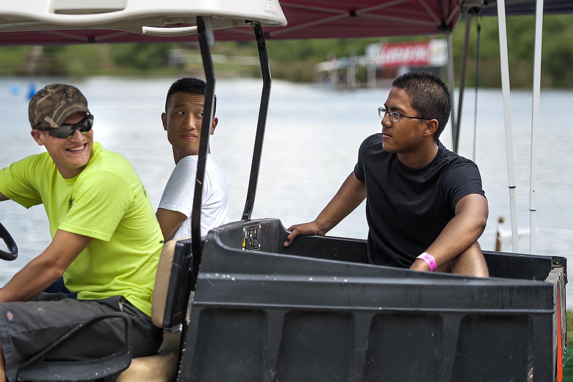 Airman Roger-Donathan D. Soeu, Goodfellow Air Force Base 316th Training Squadron student, rides on the back of a golf cart during the 2015 showdown in San Angelo Super Nationals drag boat races at Lake Nasworthy in San Angelo, Texas, June 27. Soeu and his fellow Airmen volunteered at the event to remove trash and recyclables from the area. (U.S. Air Force photo by Airman 1st Class Devin Boyer/Released)