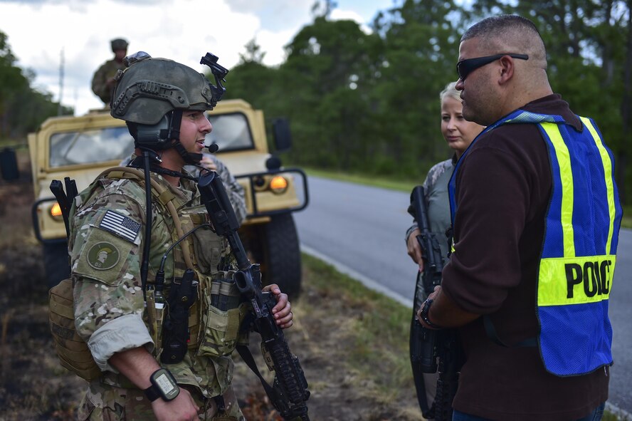 Senior Airman Caleb Brooks, 1st Special Operations Security Forces Squadron Deployed Aircraft Ground Response Element, speaks with simulated host nation nationals at a checkpoint during a field training exercise in Fort Walton Beach, Fla., June 19, 2015. The FTX simulated the DAGRE team escorting a finance specialist to make a transfer of funds. (U.S. Air Force photo/Senior Airman Jeff Parkinson)