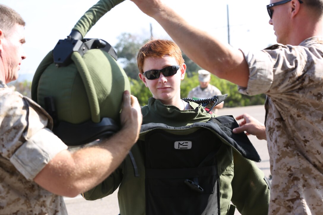 A boy dons a protective jacket and helmet typically worn by explosives ordnance disposal (EOD) technicians to withstand explosions during the Devil Dog Family Day aboard Marine Corps Air Station Miramar, California, June 26. The EOD technicians explained the purpose of the equipment they use to Marines, spouses and children.