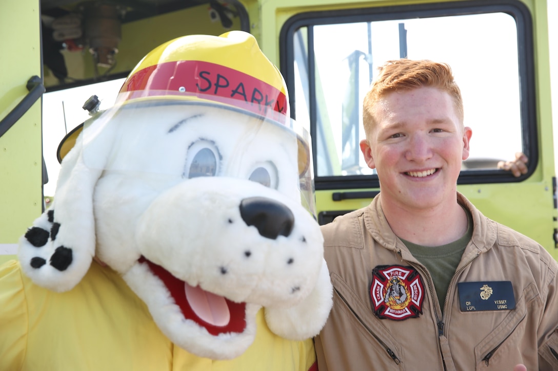 Sparky, left, the Aircraft Rescue and Firefighting (ARFF) mascot, and Lance Cpl. Cole Vessey, a firefighter with ARFF and a Tualatin, Oregon native, pose at ARFF’s static display during the Devil Dog Family Day aboard Marine Corps Air Station Miramar, California, June 26. A handful of ARFF Marines presented a firetruck and examples of equipment to Marines, spouses and children.