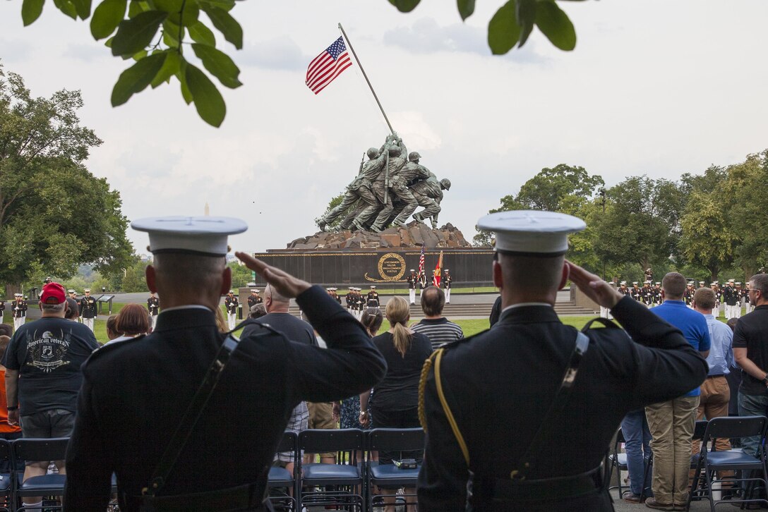 U.S. Marines with Marine Barracks Washington,D.C., salute the colors during a sunset parade at the Marine Corps War Memorial, Arlington, Va., June 30, 2015. The Honorable Mr. Ashton B. Carter, Secretary of Defense, was the guest of honor for the parade, and Gen. Joseph F. Dunford Jr., commandant of the U.S. Marine Corps, was the hosting official. Since September 1956, marching and musical units from Marine Barracks Washington, D.C., have been paying tribute to those whose“uncommon valor was a common virtue” by presenting sunset parades in the shadow of the 32-foot high figures of the United States Marine Corps War Memorial. (U.S. Marine Corps photo by Lance Cpl. Alejandro Sierras/Released)