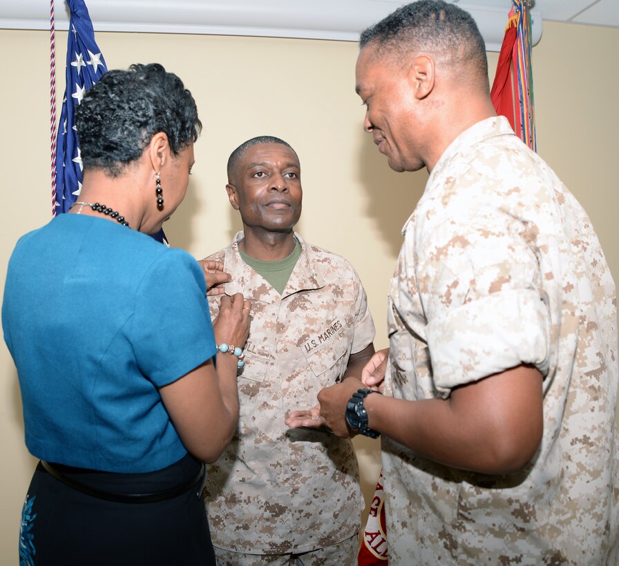Maj. Gen. Craig C. Crenshaw, commanding general, Marine Corps Logistics Command, keeps a watchful eye as Shari Carroll pins the rank of colonel onto her husband, then Lt. Col. James C. Carroll III, commanding officer, Marine Corps Logistics Base Albany. Carroll's promotion ceremony was held at LOGCOM, July 1.