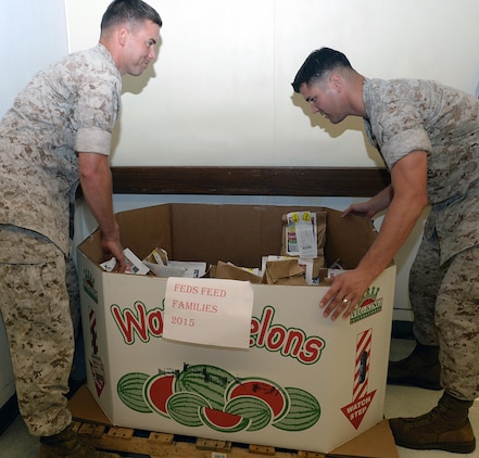 1st Lt. Ben Welch, operations officer, Military Operations and Training, (left) and Capt. Justin Jacobs, deputy public affairs officer and the "Feds Feed Families" base representative, adjust a box of donated food items at Marine Corps Logistics Base Albany’s Commissary. The base’s Commissary is among commissaries serving as collection points for the “Feds Feed Families” campaign, which ends Aug. 31 at participating stateside military installations. During this campaign, participating installations help collect items most needed by food pantries and then donate them to area food banks.