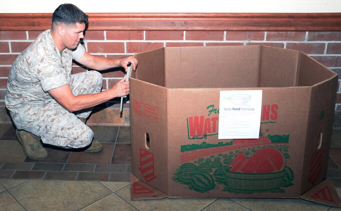 Capt. Justin Jacobs, deputy public affairs officer and the "Feds Feed Families" base representative, sets up a box for donated food items at Marine Depot Maintenance Command aboard Marine Corps Logistics Base Albany, July 1. MCLB Albany’s Commissary is among commissaries serving as collection points for the “Feds Feed Families” campaign, which ends Aug. 31 at participating stateside military installations. During this campaign, participating installations help collect items most needed by food pantries and then donate them to area food banks.