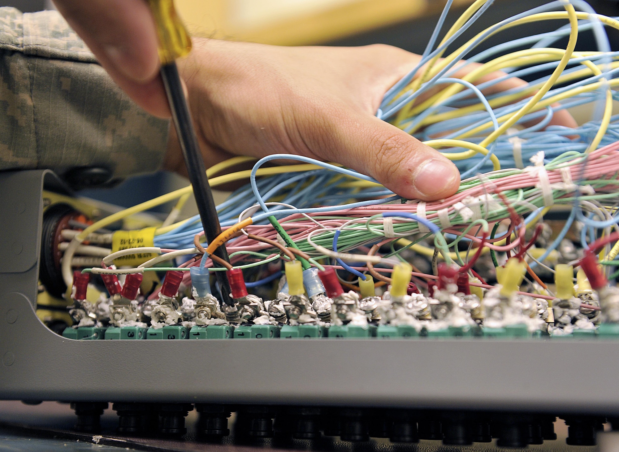 U.S. Air Force Airman 1st Class Luis Andrade, 18th Component Maintenance Squadron electrical and environmental journeyman, unscrews an F-15C Eagle essential bus circuit breaker panel on Kadena Air Base, Japan, June 25, 2015. The panel interrupts the flow of electricity to prevent a system or component failure downstream of the circuit breaker, ensuring the F-15s' capability to provide for the common defense of Japan. (U.S. Air Force photo by Naoto Anazawa/Released)