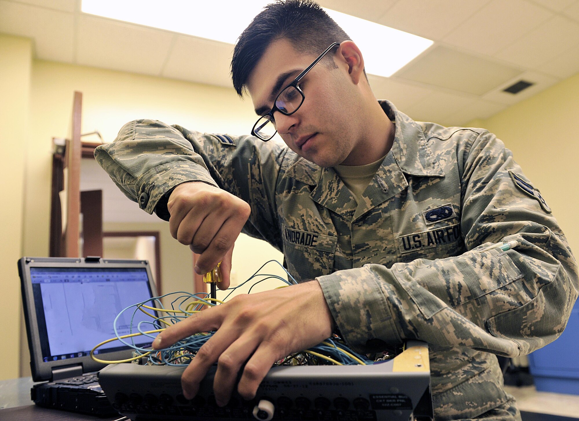 U.S. Air Force Airman 1st Class Luis Andrade, 18th Component Maintenance Squadron electrical and environmental journeyman, unscrews an F-15C Eagle essential bus circuit breaker panel on Kadena Air Base, Japan, June 25, 2015. The breaker's purpose is to prevent the systems from failing and to reduce the risk of electrical fire by shutting off power to failed systems. (U.S. Air Force photo by Naoto Anazawa/Released)