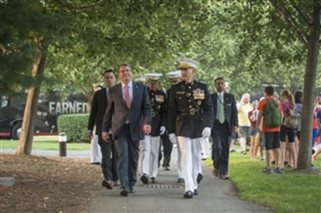 Defense Secretary Ash Carter walks with Marine Corps Commandant Gen. Joseph Dunford as they arrive at the U.S. Marine Corps War Memorial in Arlington, Va., for the Sunset Parade, June 30, 2015. Carter was the parade's guest of honor.
