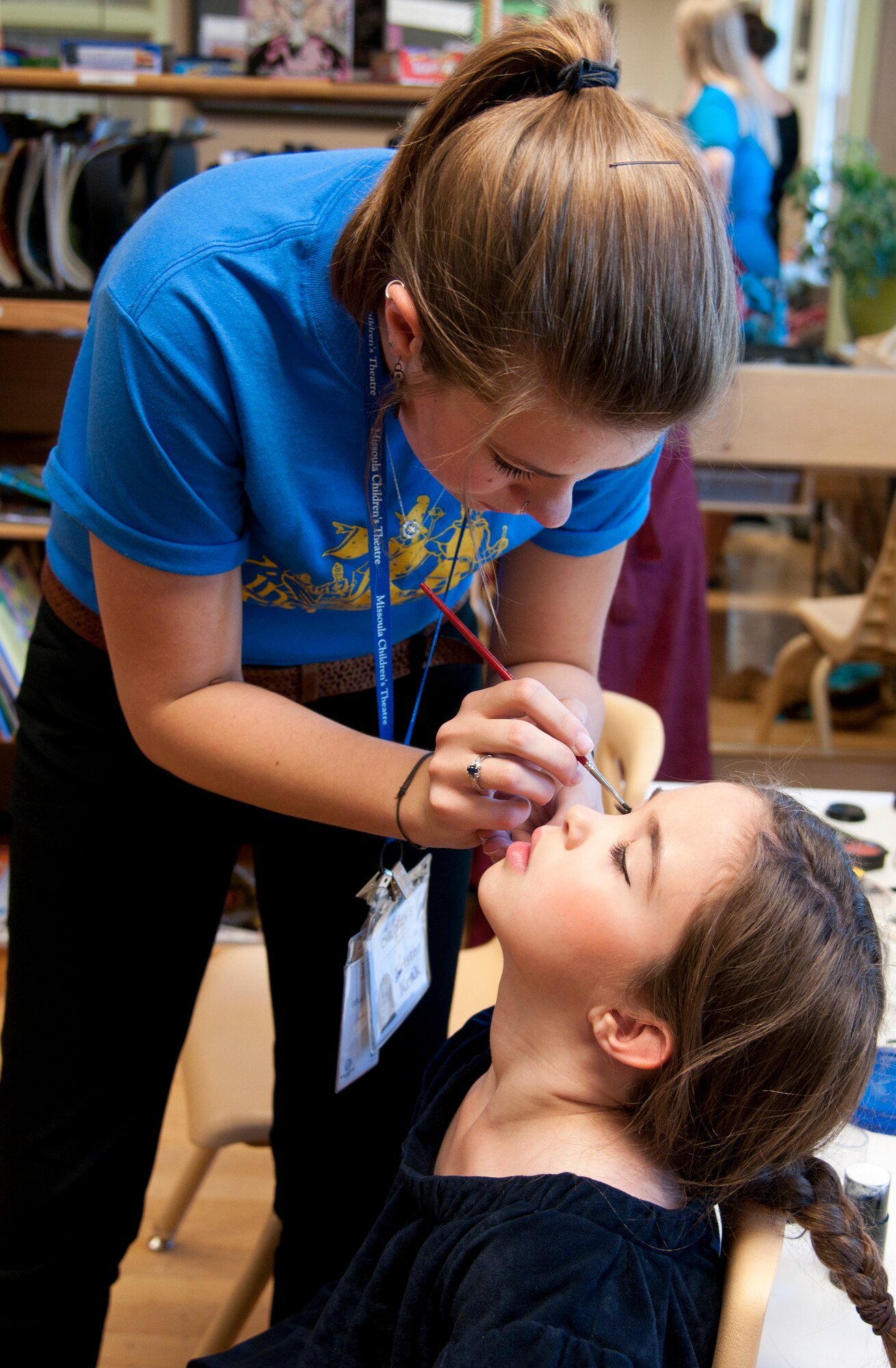 Kristen Krak, Missoula Children’s Theatre Tour actor and director, applies make-up to Aubreu Borecki, daughter of Master Sgt. Ricardo Borecki, 90th Logistics Readiness Squadron first sergeant, before the start of the play “King Arthur’s Quest.” The children rehearsed for four and a half days before the final performance. (U.S. Air Force photo by Airman 1st Class Malcolm Mayfield)