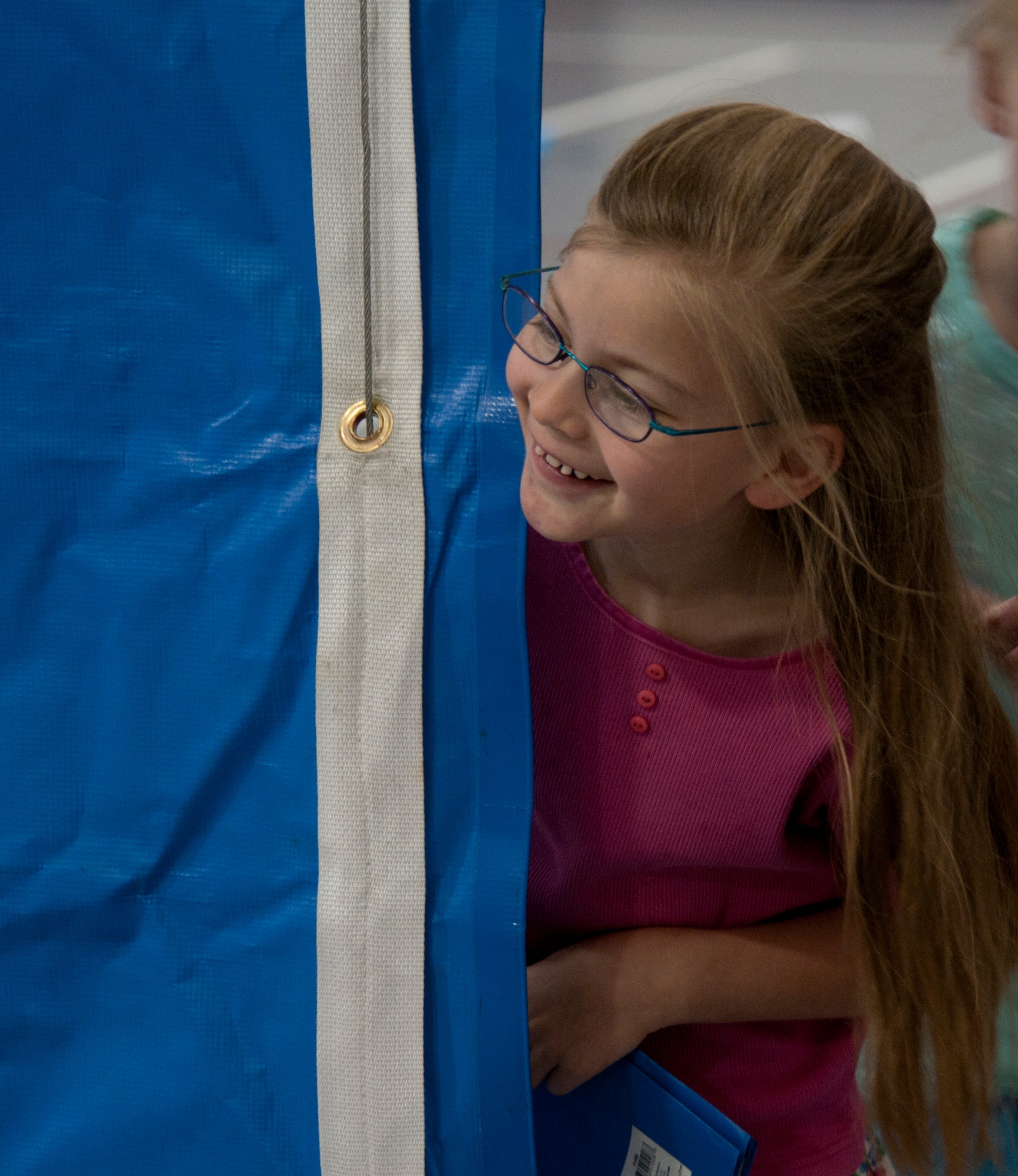 Anne Ritschard, daughter of Col. Hans Ritschard, 90th Medical Group commander, peeks round a curtain June 23, 2015, in the Youth Center on F.E. Warren Air Force Base, Wyo., during a break from rehearsal for the play King Arthur’s Quest. Thirty-one children were casted in the play performed on June 26 in the Youth Center gym. (U.S. Air Force photo by Airman 1st Class Malcolm Mayfield)