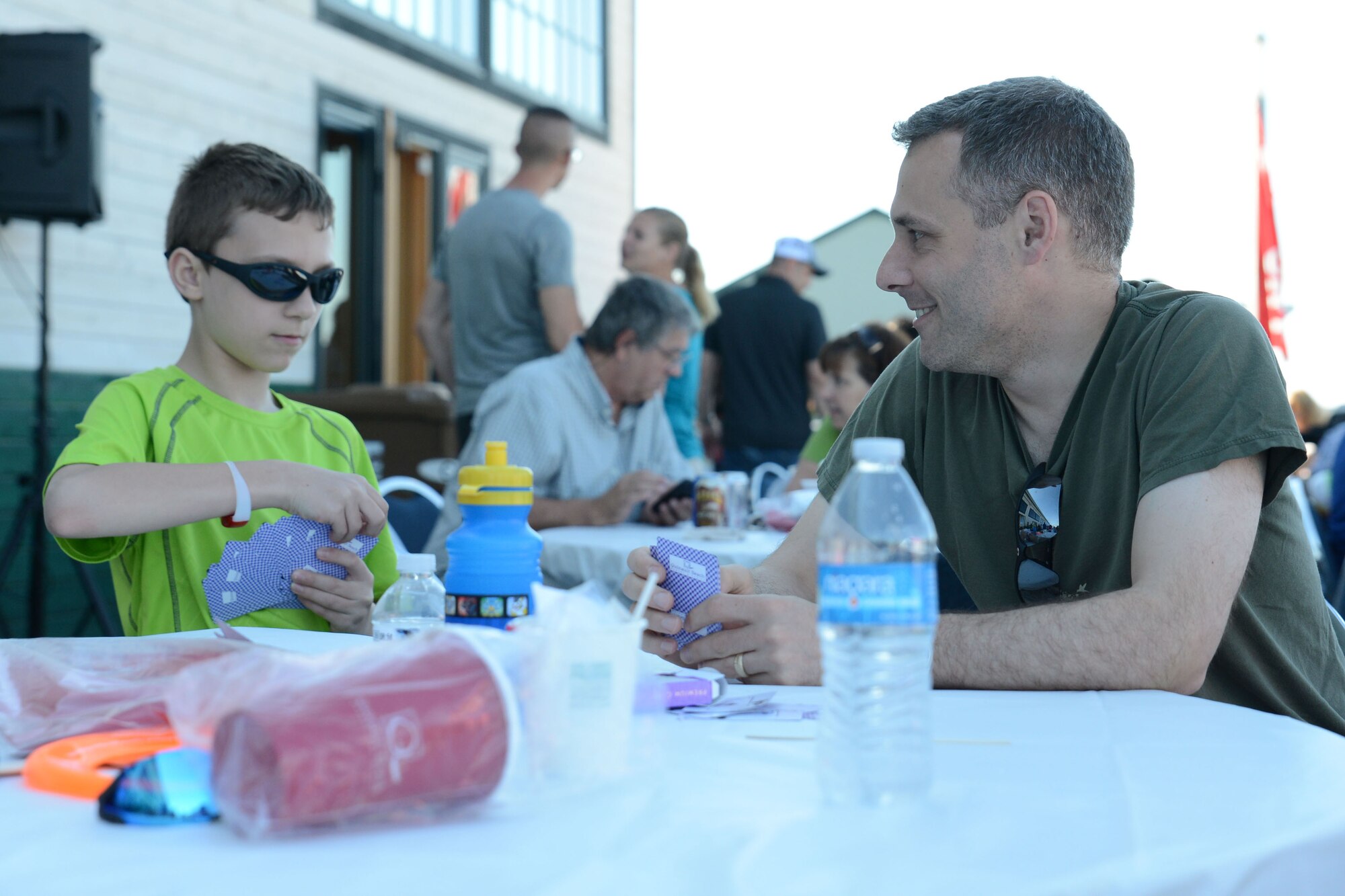 Lt. Col. John Rozsnyai, 62nd Airlift Wing director of staff, plays a game of cards with his son June 29, 2015, in Tacoma, Wash., during the 2015 Airman Appreciation Day. The first year for Airman Appreciation Night was 2014, and Mayor Marilyn Strickland, the Mayor of Tacoma named June 29, Tacoma’s official Airmen Day. (U.S. Air Force photo\Staff Sgt. Katie Jackson)