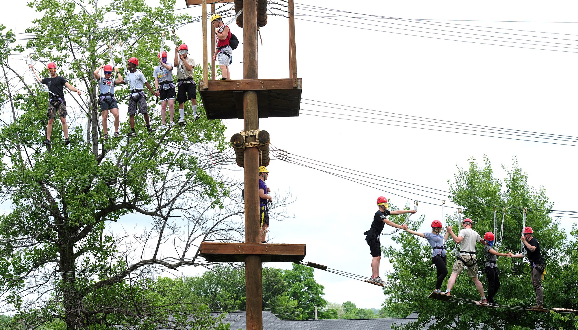Members from Whiteman Air Force Base, Mo., clasp hands as they make their way across The Odyssey Course June 17, 2015, at the Tucker Leadership Lab in Liberty, Mo. The Odyssey is a high challenge course, where participants climb a net to one of two levels then as a team, make their way across four challenges. (U.S. Air Force photo by Airman 1st Class Jazmin Smith/Released)