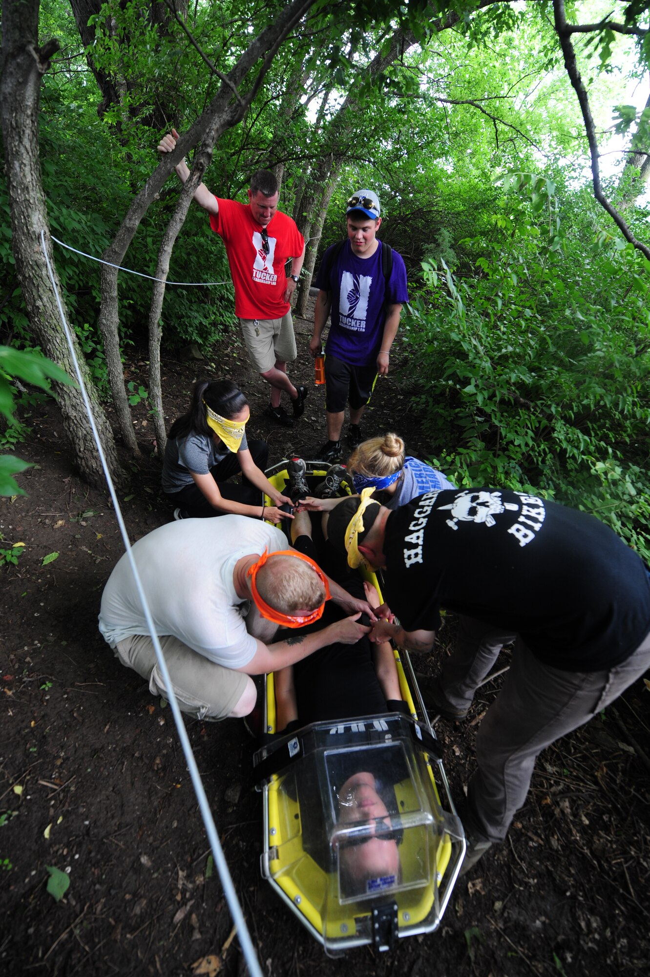 Members from Whiteman Air Force Base, Mo., participate in a “rescue-escape” challenge June 17, 2015, as part of the Tucker Leadership Lab in Liberty, Mo. During this challenge, Airmen used communication, trust and teamwork to carry an “injured” Wingman through an array of obstacles, guided only by a string and knowledge from those guiding the group. (U.S. Air Force photo by Airman 1st Class Jazmin Smith/Released)