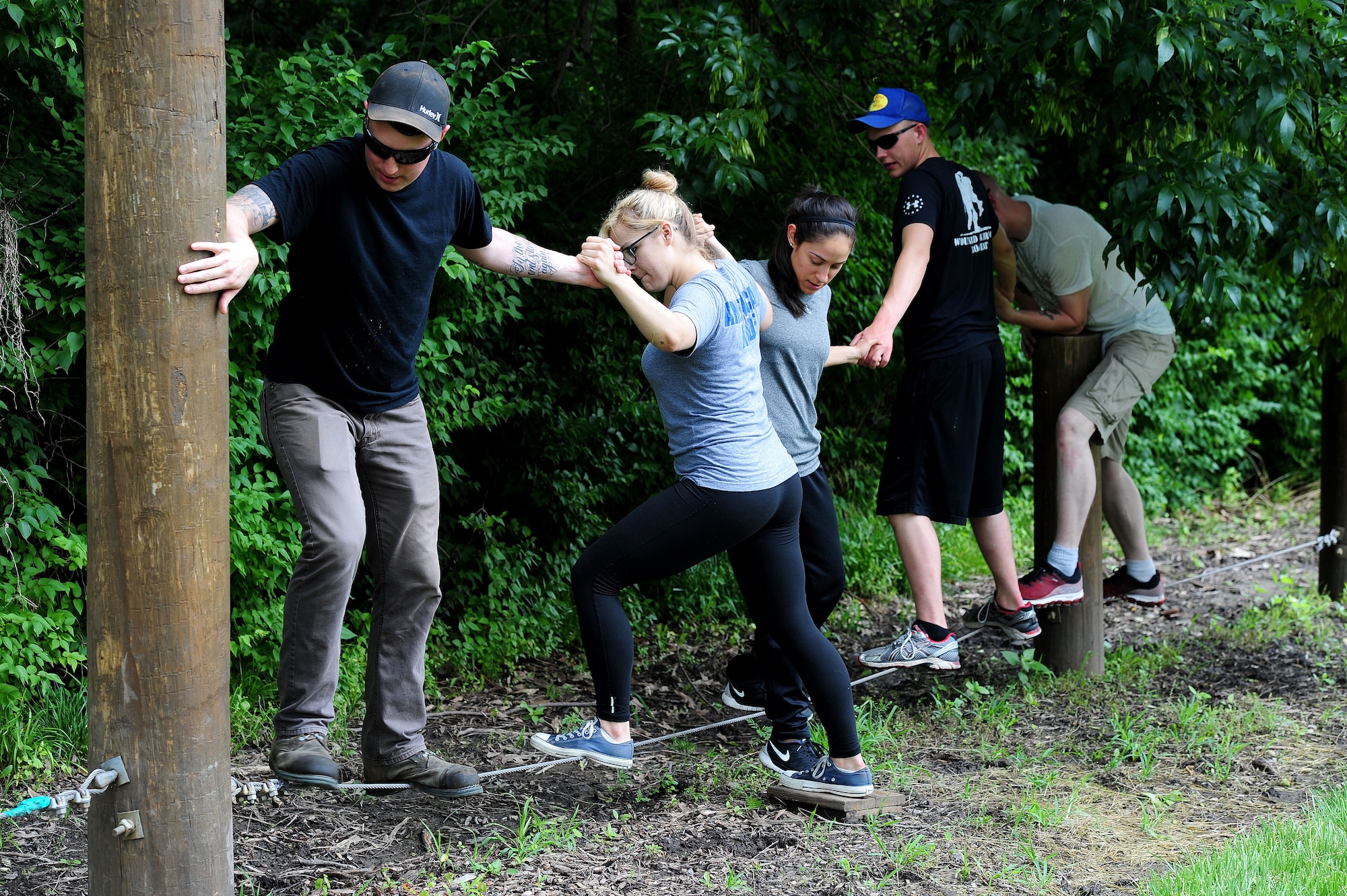 Members from Whiteman Air Force Base, Mo., participate in a low challenge course June 17, 2015, as part of the Tucker Leadership Lab in Liberty, Mo. The Airmen had to navigate across several beams while keeping their hands linked and communicating to a blindfolded team member. (U.S. Air Force photo by Airman 1st Class Jazmin Smith/Released)