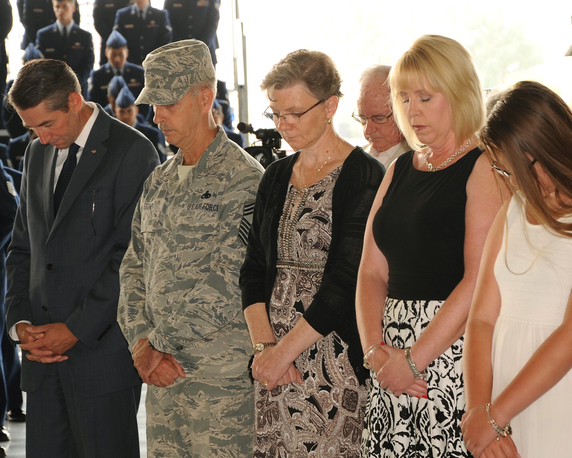 Families, distinguished guests and Airmen bow their heads during the invocation before the 319th Air Base Wing change of command ceremony on Grand Forks Air Force Base, N.D. on July 1, 2015. Col. Rodney Lewis assumed command of the 319th ABW from Col. Paul Bauman. (U.S. Air Force Photo by Senior Airman Zachiah Roberson)