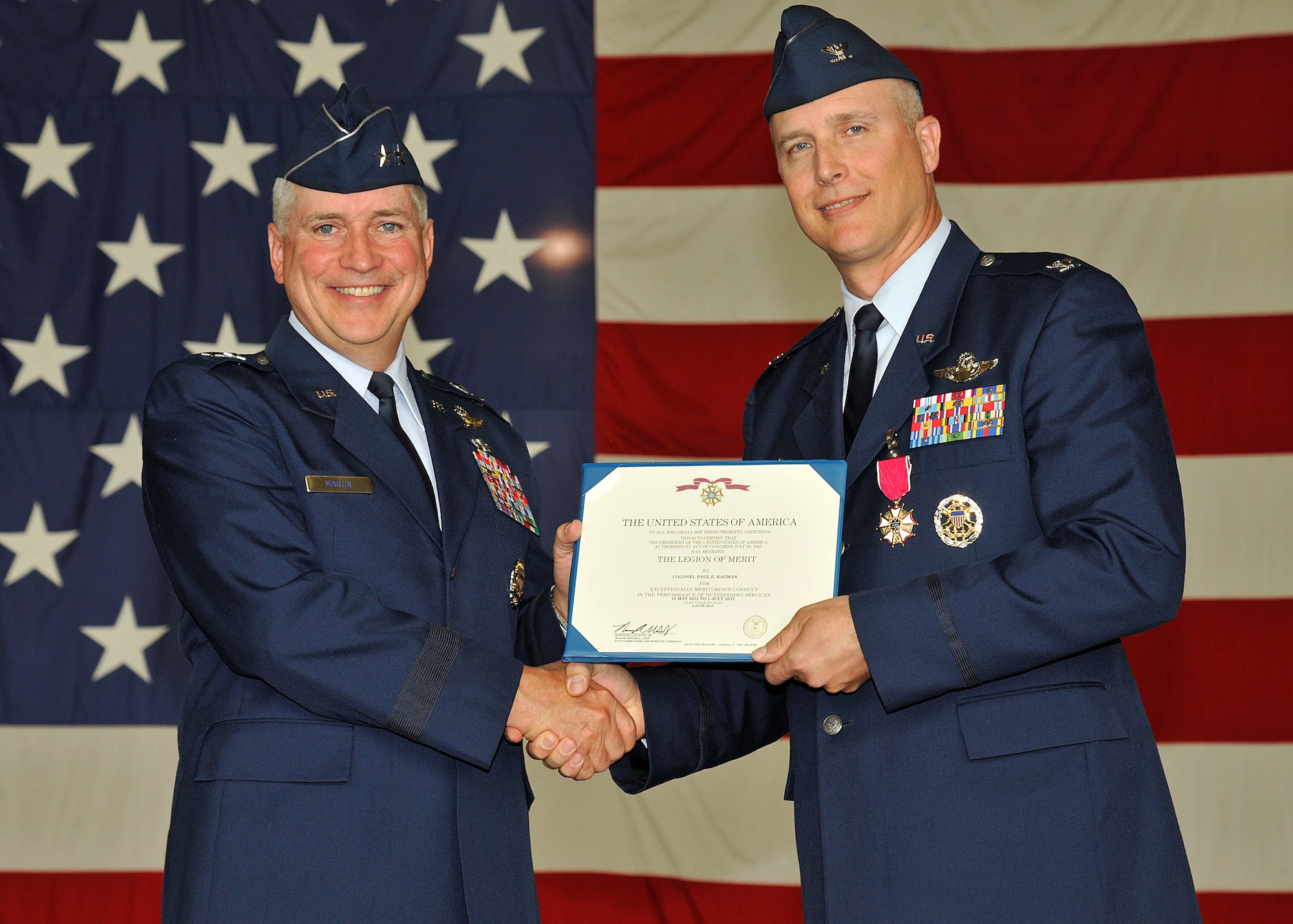 Maj. Gen. Frederick H. Martin, U.S. Air Force Expeditionary Center commander, presents Col. Paul Bauman, outgoing 319th Air Base Wing commander, a certificate of the Legion of Merit on July 1, 2015, during the 319th ABW change of command on Grand Forks Air Force Base, N.D. The Legion of Merit is awarded for an exceptionally meritorious conduct in the performance of outstanding services to the U.S. (U.S. Air Force Photo by Senior Airman Xavier Navarro/released)