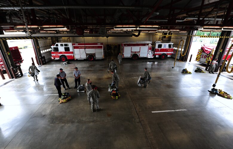 Airmen from the 509th Civil Engineer Squadron perform a gear check in the fire truck bay at Whiteman Air Force Base, Mo., May 28, 2015. After morning formation, firefighters tend to their assigned duties and training. (U.S. Air Force photo by Senior Airman Keenan Berry/Released)