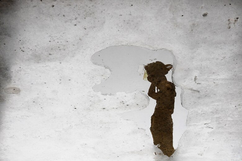 The reflection of Airman 1st Class Luis Betancur, 509th Civil Engineer Squadron firefighter, is shown in a puddle as he dons a helmet at Whiteman Air Force Base, Mo., May 28, 2015. Firefighters exhibit valor within their heroic deeds to instill hope in victims while facing danger. Betancur said he dreamed of being a firefighter since he was 5 years old. He was inspired by his dad’s friend, a firefighter who served for many years. (U.S. Air Force photo by Senior Airman Keenan Berry/Released)