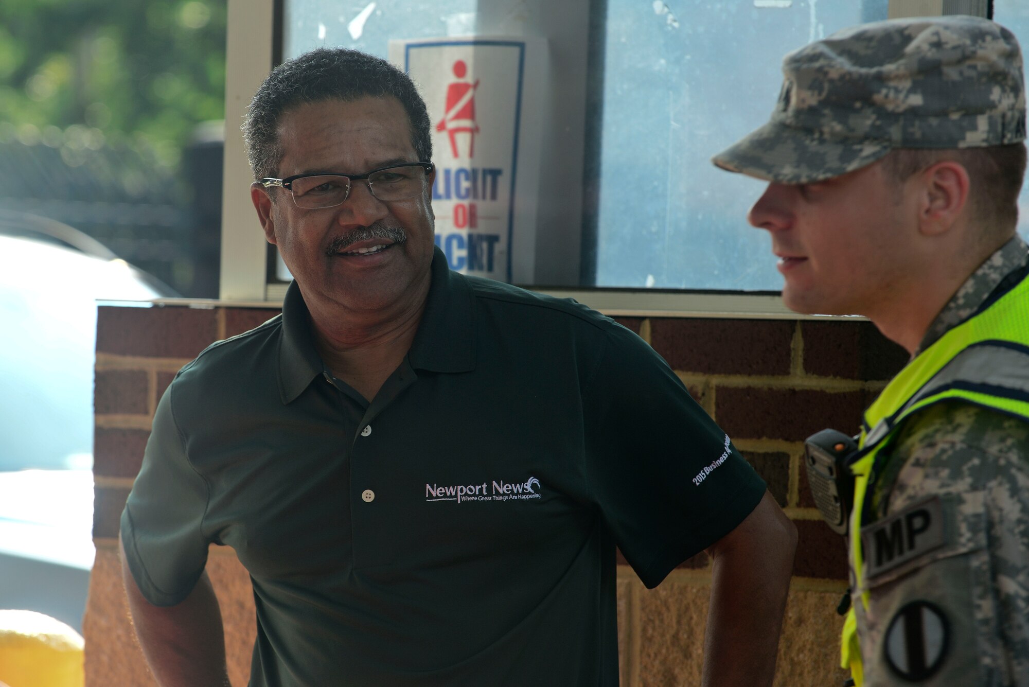 U.S. Army Sgt. Cory Anderson, 221st Military Police Detachment Military Police officer, and McKinley Price, Newport News Mayor, talk to commuters entering the installation at Fort Eustis, Va., June 25, 2015. Leadership from Newport News, Va., handed out coffee mugs to commuters as they went through the gate to say thank you for their patience during the construction of Route 105 Fort Eustis Boulevard Bridge. (U.S. Air Force photo by Senior Airman Kimberly Nagle)