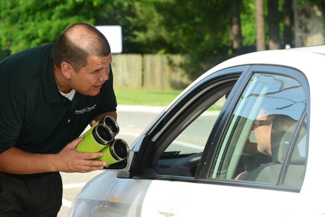 Robert Coleman, Newport News Vice Mayor, greets a commuter entering Fort Eustis, Va., June 25, 2015. Leadership from Newport News, Va., spoke with commuters at the gate and handed out coffee mugs to celebrate the completion of Route 105 Fort Eustis Boulevard Bridge. (U.S. Air Force photo by Senior Airman Kimberly Nagle)
