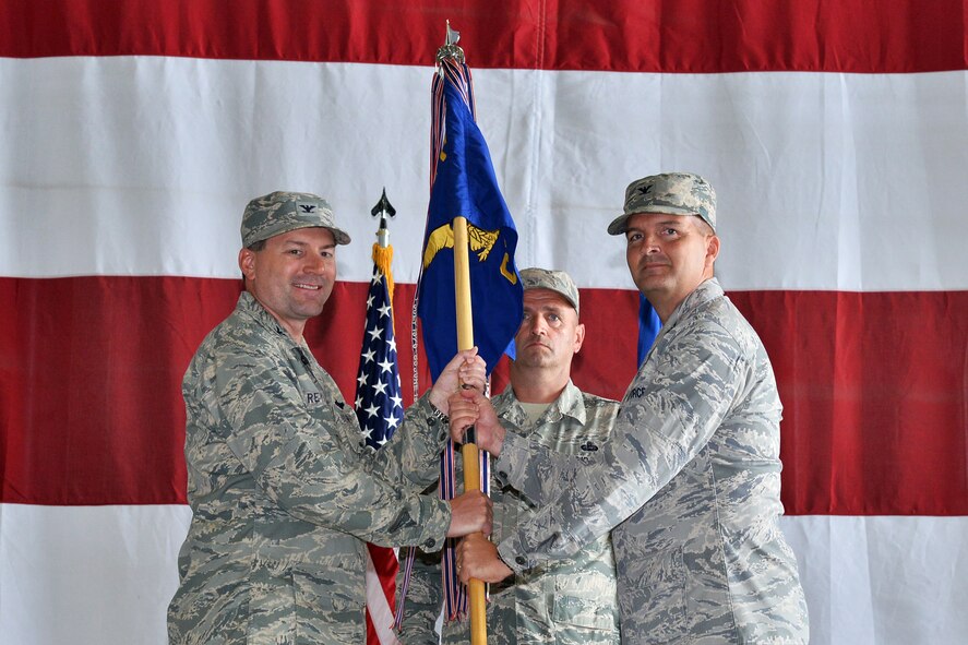 U.S. Air Force Col. Marty Reynolds, 55th Wing commander, hands the 55th Communications Group guidon to U.S. Air Force Col. Sean Murphy, signifying him as the new commander during an assumption of command ceremony June 30 at the Bennie Davis Maintenance Facility at Offutt Air Force Base, Nebraska. Murphy assumed command from U.S. Air Force Col. Jeffrey Granger, who relinquished command on June 8. (Photo by Charles Haymond)