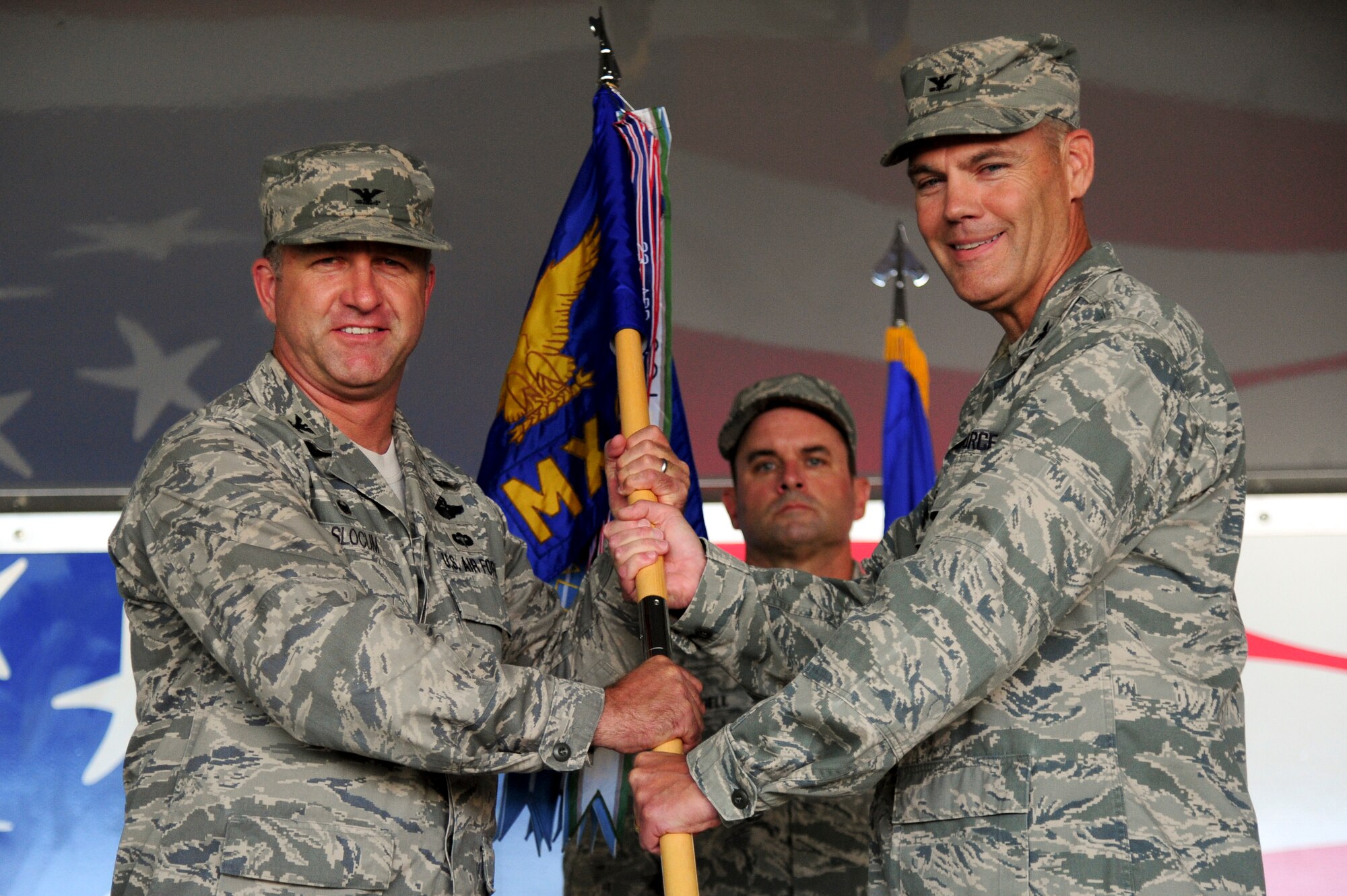Col. Darrell Steele (right), outgoing 4th Maintenance Group commander, relinquishes the guidon to Col. Mark Slocum, 4th Fighter Wing commander, during a change of command ceremony, June 29, 2015, at Seymour Johnson Air Force Base, North Carolina. Steele led the group for three years and plans to retire now that he has relinquished command. (U.S. Air Force photo/Senior Airman Brittain Crolley)