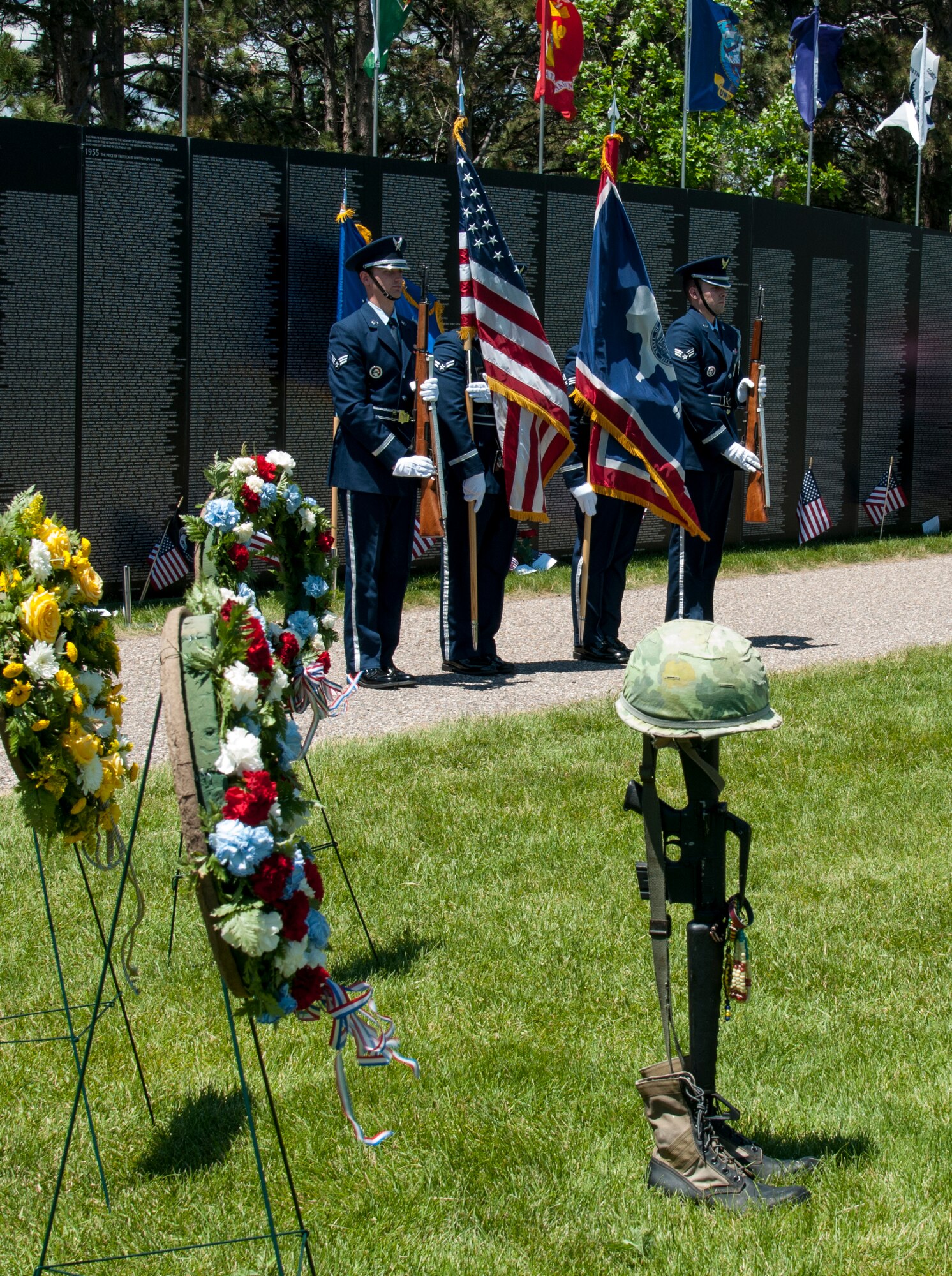 Ceremonial guardsmen from the 90th Missile Wing Honor Guard, F.E. Warren Air Force Base, Wyo., post the colors at the closing ceremony of the American Veterans Traveling Tribute visit to Cheyenne, Wyo. They stand in front of a replica of the Washington, D.C., Vietnam Veterans Memorial, which lists all the names of fallen Americans from the Vietnam War. The tribute also included displays honoring Americans who fell in other conflicts throughout U.S. history. (U.S. Air Force photo by Airman 1st Class Malcolm Mayfield)