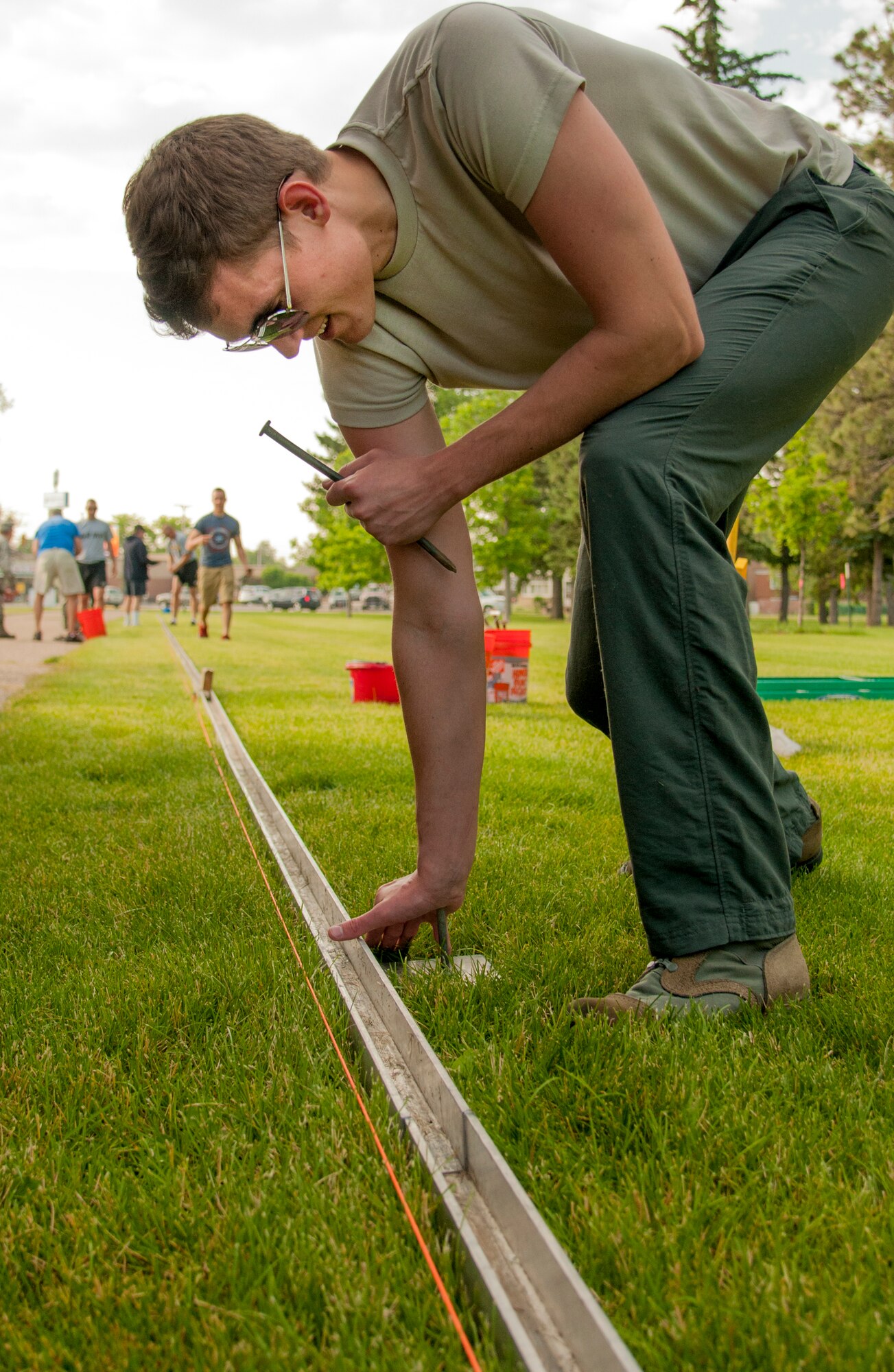 Senior Airman Jeff Grossi, 90th Missile Maintenance Squadron Personnel Reliability Program monitor, F.E. Warren Air Force Base, Wyo., secures a railing into the ground in Lion's Park, Cheyenne, Wyo., June 25, 2015. The railing later held up a replica of the Vietnam Veterans Memorial as part of the American Veterans Traveling Tribute visit to Cheyenne. Volunteers, many from F.E. Warren, helped put on the event. (U.S. Air Force photo by Senior Airman Jason Wiese)