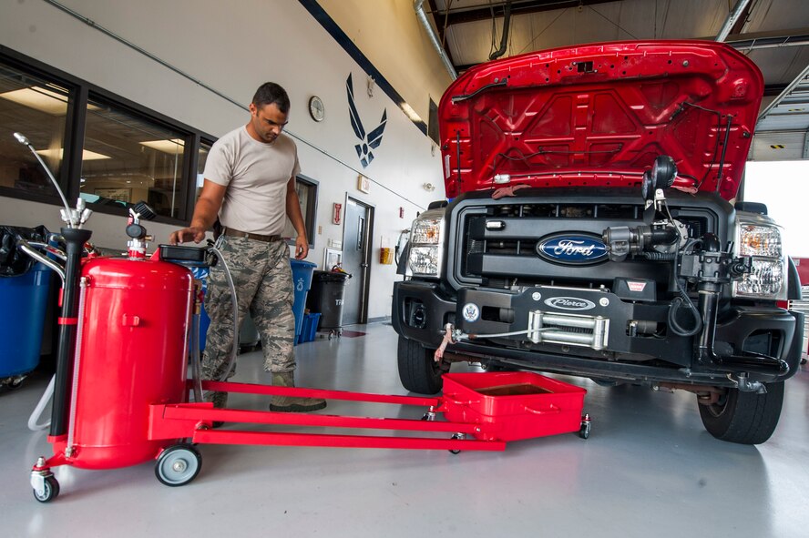 U.S. Air Force Airman 1st Class Nigell McAlpin, 23d Logistics Readiness Squadron special vehicle maintenance journeyman, prepares to perform an oil change June 30, 2015, at Moody Air Force Base, Ga. McAlpin utilized an oil change disposal device to safely store the waste. (U.S. Air Force photo by Airman 1st Class Dillian Bamman/Released)