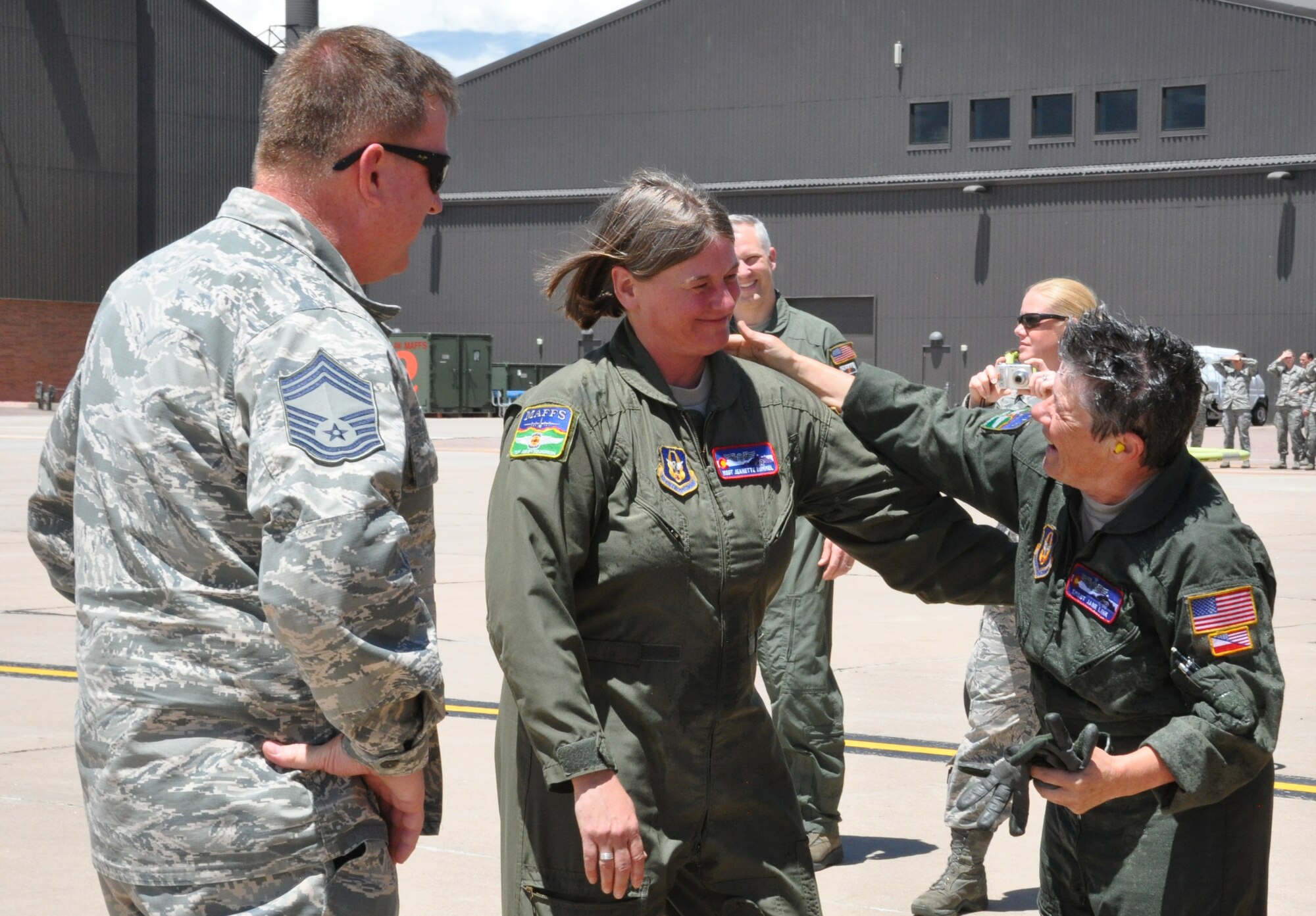 PETERSON AIR FORCE BASE, Colo. – Senior Master Sgt. Jane Link (far right) receives congratulations from fellow C-130 flight engineer, Master Sgt. Jeanette Rummel and Chief Master Sgt. Dave Carey, 731st Airlift Squadron chief flight engineer,  after the return of Link’s fini-flight, June 6, 2015 here.  Link was later honored for her nearly 22-year Air Force career that spanned over four decades during her retirement ceremony later that day. (U.S. Air Force photo/Ann Skarban)