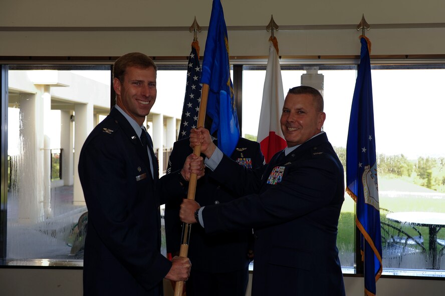 U.S. Air Force Col. David J. Roll, newly appointed commander of the 18th Aeromedical Evacuation Squadron, accepts the 18th AES guidon from Col. David A. Mineau, 18th Operations Group commander, during a change of command ceremony on Kadena Air Base, Japan, June 26, 2015. The 18th AES has a large presence in the Pacific with momentous medical operations. (U.S. Air Force photo by Airman 1st Class Lynette Rolen)