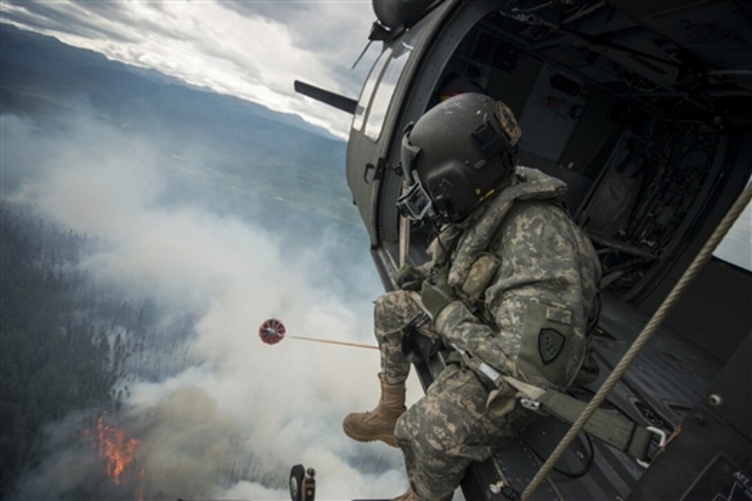 Army Sgt. Philip Peter looks out from a UH-60 Black Hawk helicopter while dropping water from a bambi bucket to support firefighting efforts near Tok, Alaska, June 26, 2015. Peter is a crew chief assigned to the Alaska National Guard's 1st Battalion, 207th Aviation Regiment.